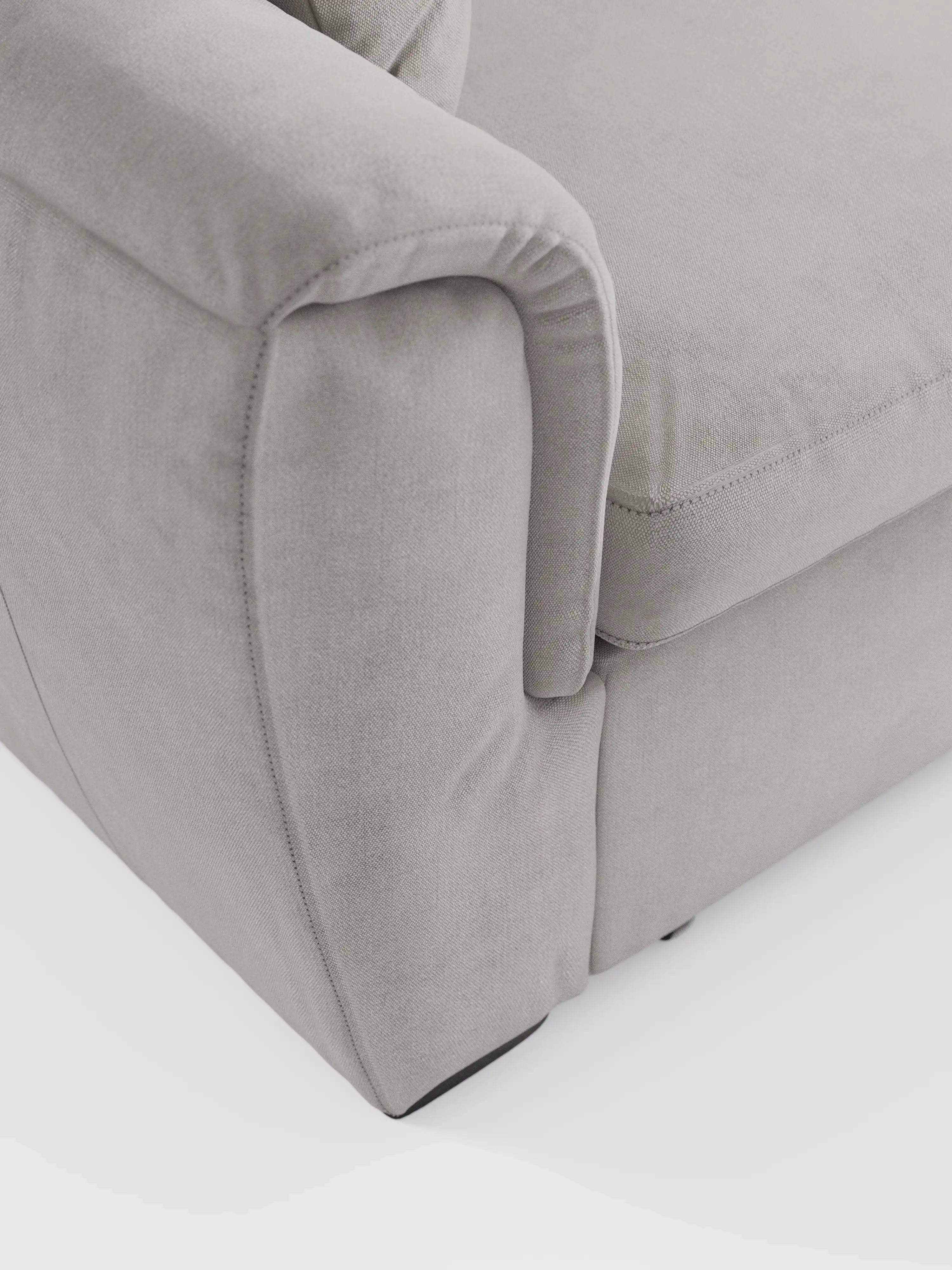 Primo piano del divano Titano a 2 posti estraibile con poggiatesta reclinabili in tessuto smacchiabile Oeko-Tex® di Divani.Store, con particolare attenzione ai moderni cuscini dei braccioli e della seduta in grigio chiaro. L’immagine mette in risalto il rivestimento liscio e facile da pulire del divano, le cuciture precise e la consistenza morbida e soffice. Sullo sfondo bianco, il colore neutro e il design contemporaneo di questo divano compatto risultano ancora più evidenti.