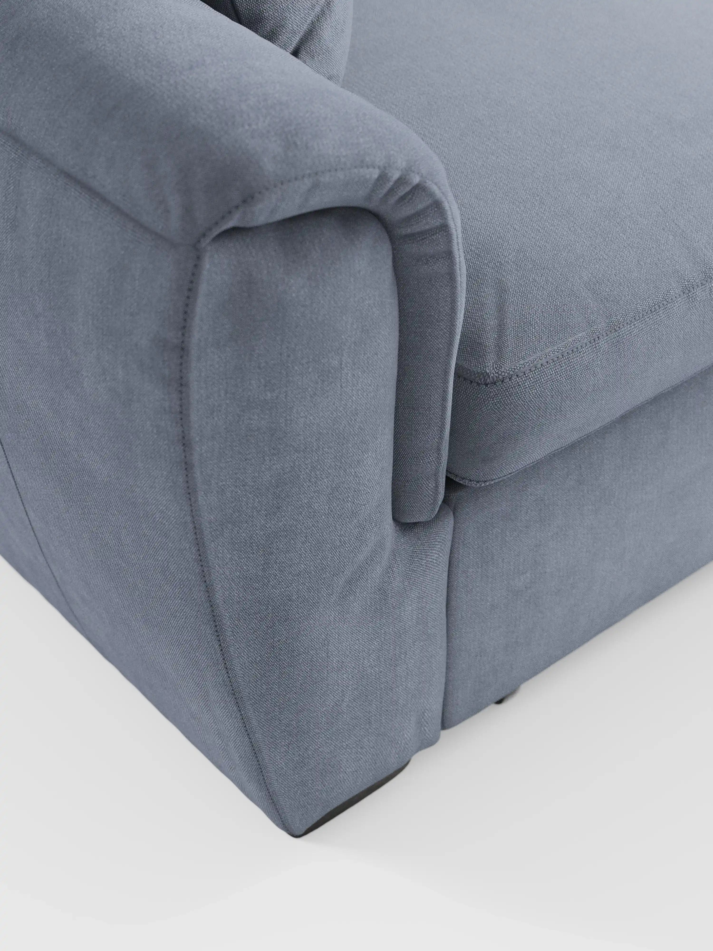 Primo piano del bracciolo e della seduta del divano Titano a 2 posti estraibile con poggiatesta reclinabili in tessuto smacchiabile Oeko-Tex® di Divani.Store, raffigurato in un moderno tessuto grigio chiaro su sfondo bianco. Il rivestimento morbido e facile da pulire presenta cuciture a vista e un'imbottitura soffice che garantisce comfort e un look contemporaneo. La silhouette versatile di questo divano compatto coniuga perfettamente stile e funzionalità, rendendolo la scelta ideale per gli spazi moderni.