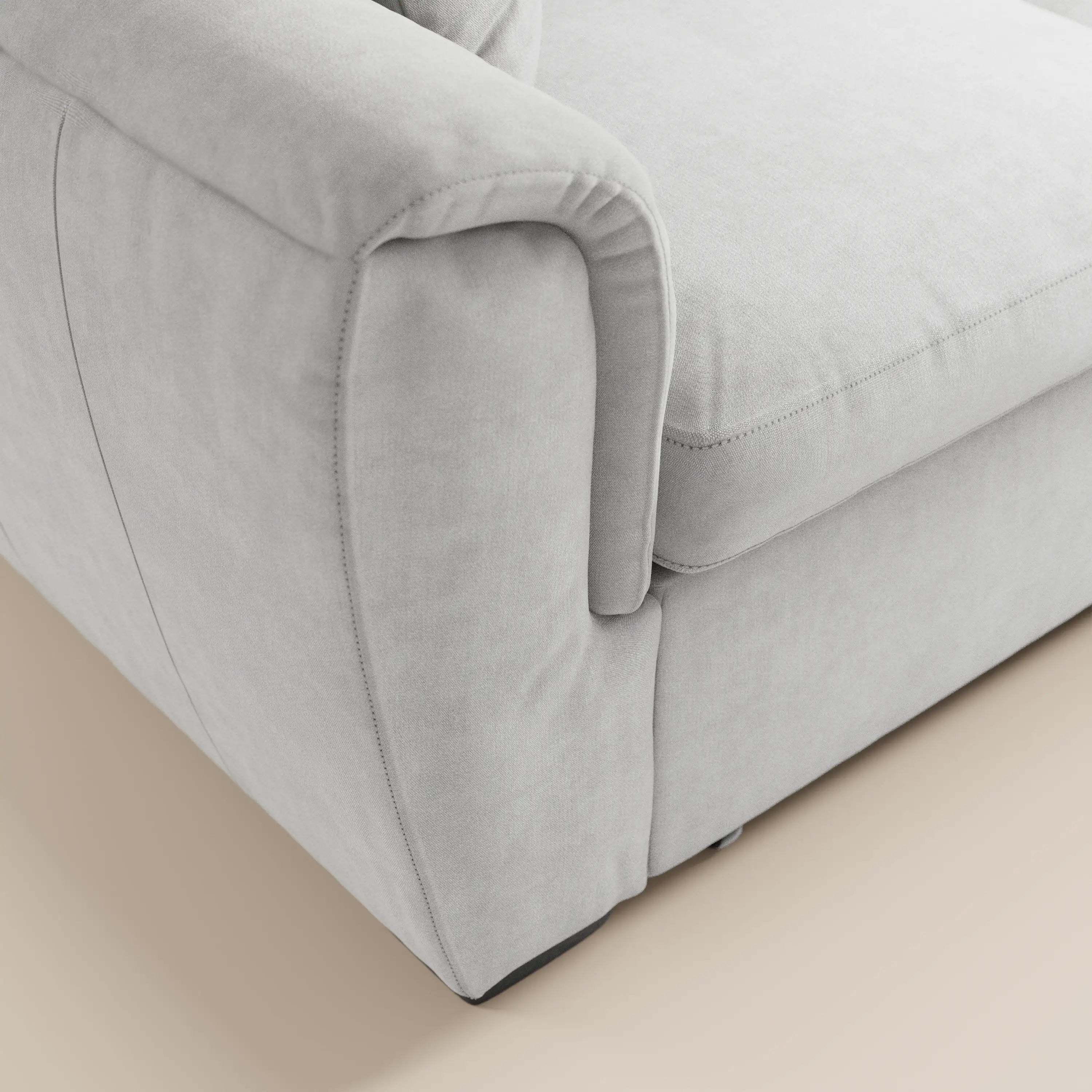 Primo piano del divano a 2 posti estraibile Titano di Divani.Store, caratterizzato da un tessuto grigio chiaro resistente alle macchie certificato Oeko-Tex®, cuciture curate e poggiatesta reclinabili. I braccioli arrotondati e le linee pulite ne esaltano il design moderno su un pavimento beige.