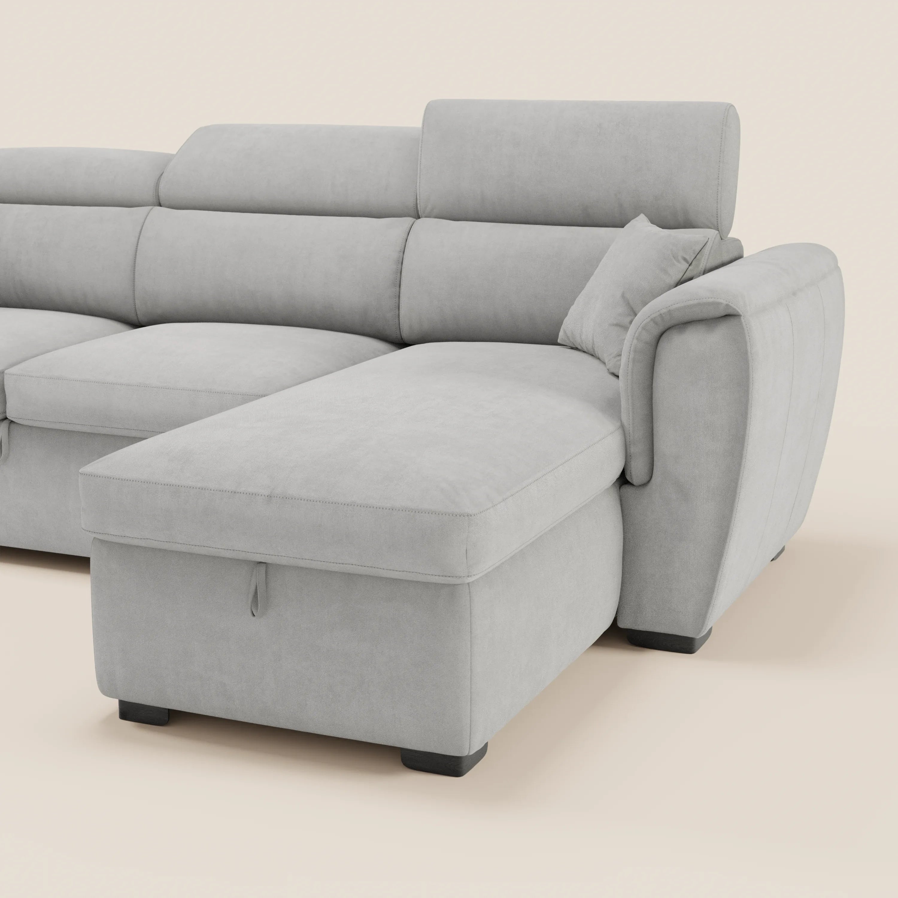 Il divano letto Titano con penisola reversibile di Divani.Store è realizzato in tessuto lavabile, è dotato di poggiatesta reclinabili, di un elemento estraibile e di un vano contenitore. Nella foto è raffigurato in grigio chiaro con piedini a blocco neri su uno sfondo beige a tinta unita.
