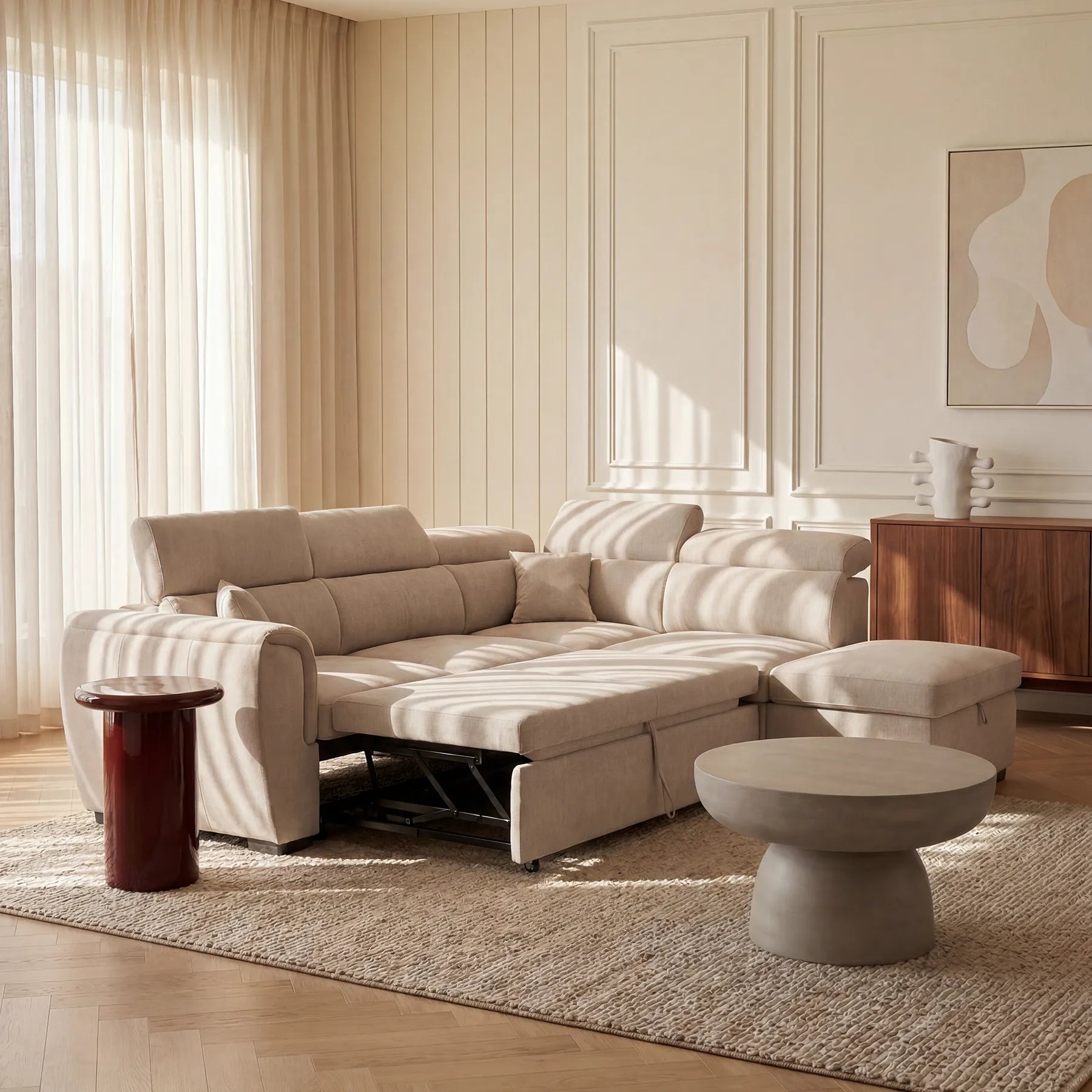 Un divano angolare reversibile Titano color beige di Divani.Store, con elemento estraibile e pouf contenitore, è posizionato su un tappeto dalla trama rigata in una stanza inondata di luce, accanto a un tavolino rotondo grigio chiaro, a un tavolino rosso lucido e a un mobile in legno in stile mid-century.