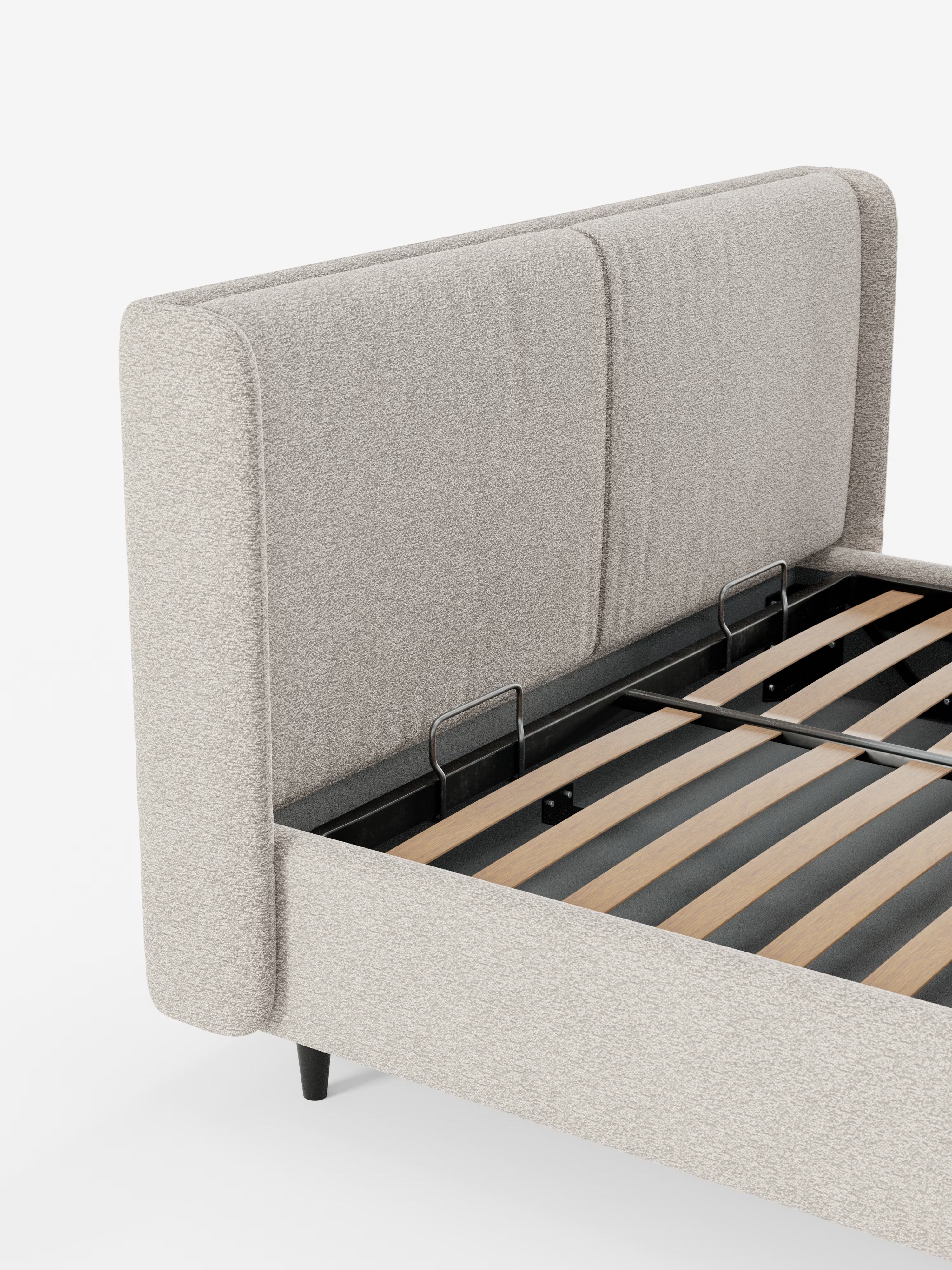 Un letto di design contemporaneo VALKIRIA di Letti.store, caratterizzato da una testiera avvolgente in tessuto beige chiaro certificato Oeko-Tex® con due cuscini imbottiti, gambe nere e doghe in legno a vista. L'immagine in primo piano mostra l'angolo e una parte della testiera, mettendo in risalto i dettagli minimalisti che incarnano un design contemporaneo.