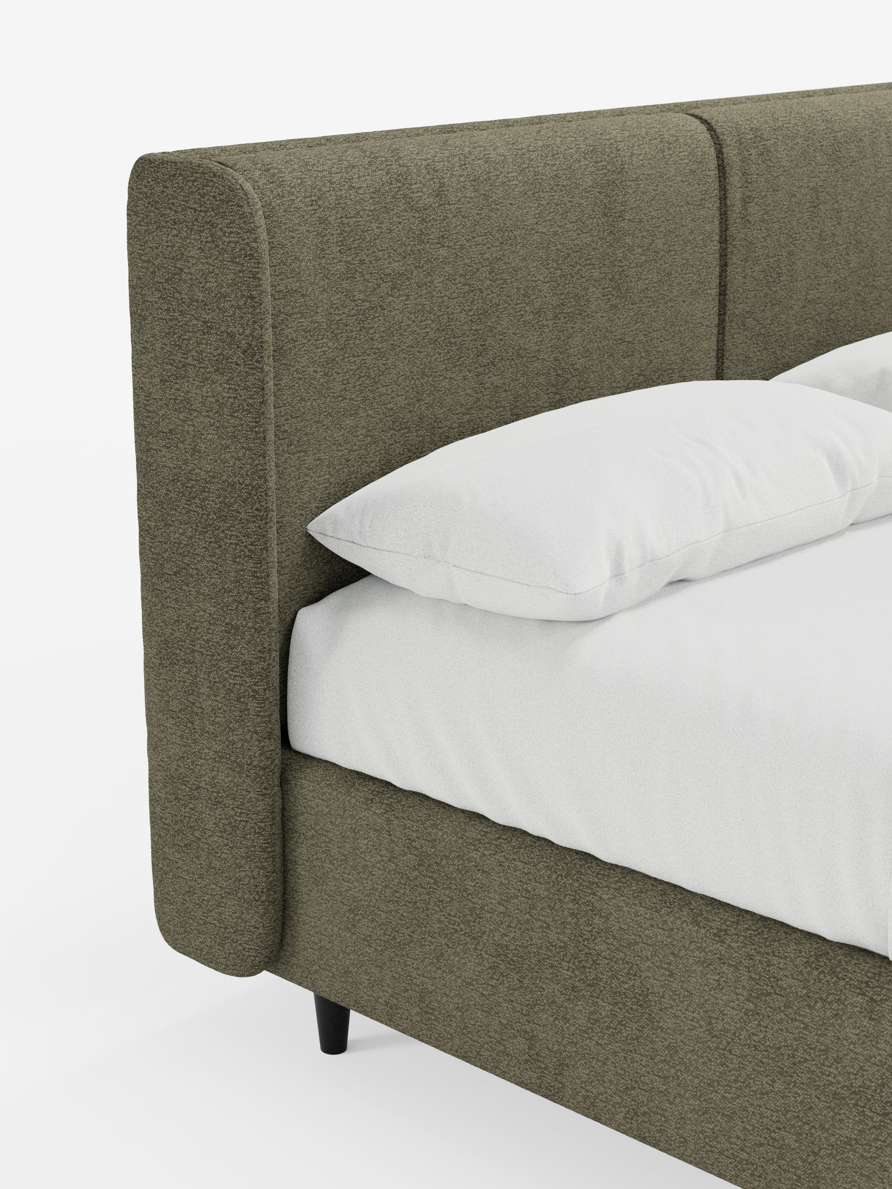 Un primo piano del letto di design VALKIRIA con contenitore e testiera avvolgente di Letti.store mette in risalto un angolo letto imbottito in tessuto Oeko-Tex® verde oliva a trama ruvida, caratterizzato da un’alta testiera imbottita con due morbidi cuscini. Il design contemporaneo prevede un cuscino bianco e la biancheria da letto disposti sulla struttura, che poggia su corte gambe nere su uno sfondo chiaro e semplice.