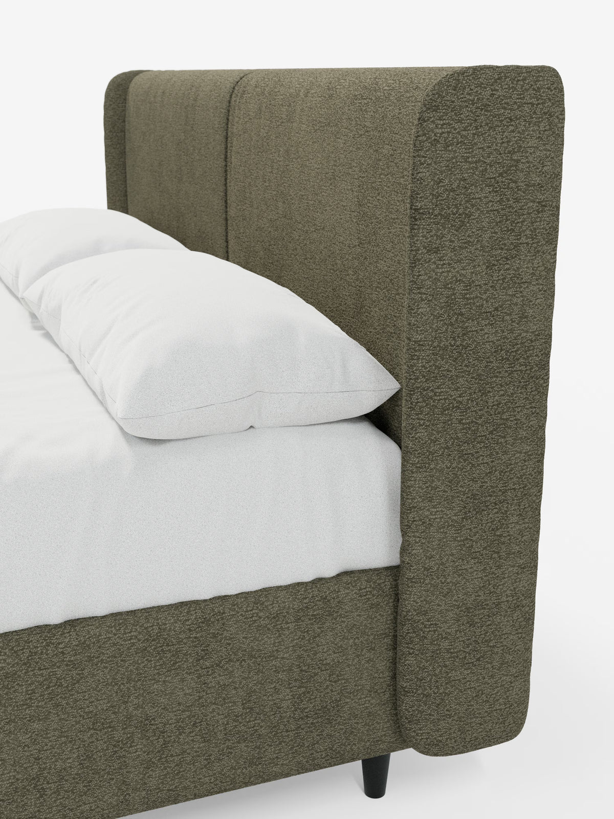Un primo piano del letto di design VALKIRIA con vano contenitore e testiera avvolgente di Letti.store ne mette in risalto lo stile contemporaneo, caratterizzato da un tessuto Oeko-Tex® verde oliva con finitura testurizzata. La testiera alta e imbottita, con cuciture verticali e due morbidi cuscini, emana l’eleganza e il comfort tipici di un letto imbottito moderno. Il materasso e il cuscino bianchi sono parzialmente visibili, mentre il letto poggia su corte gambe cilindriche nere su uno sfondo bianco a