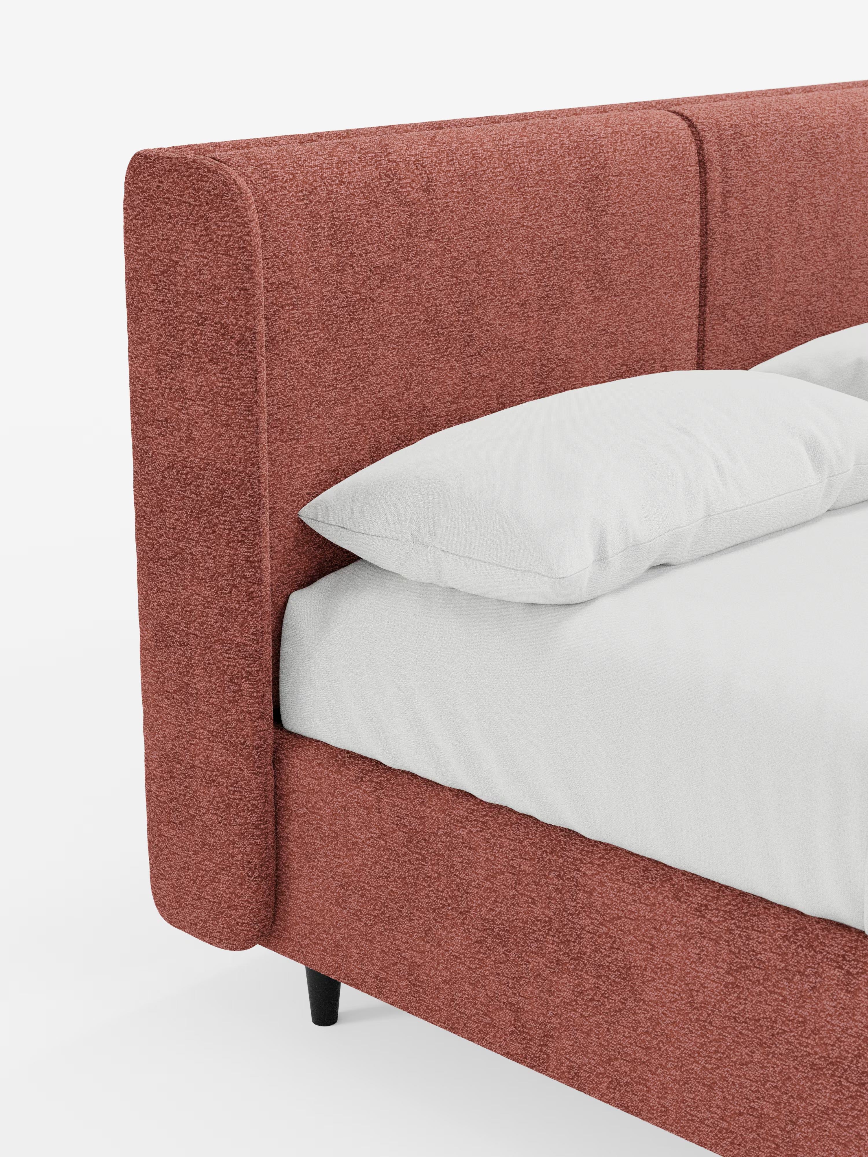 Un letto di design contemporaneo VALKIRIA di Letti.store, caratterizzato da una struttura imbottita in una calda tonalità di marrone-rossastro certificata Oeko-Tex®, una testiera avvolgente con due cuscini imbottiti e un pratico vano portaoggetti. Il letto è rifinito con cura con un cuscino bianco e un lenzuolo con angoli, presentato su uno sfondo bianco a tinta unita che ne esalta le linee moderne e il caratteristico pannello laterale.