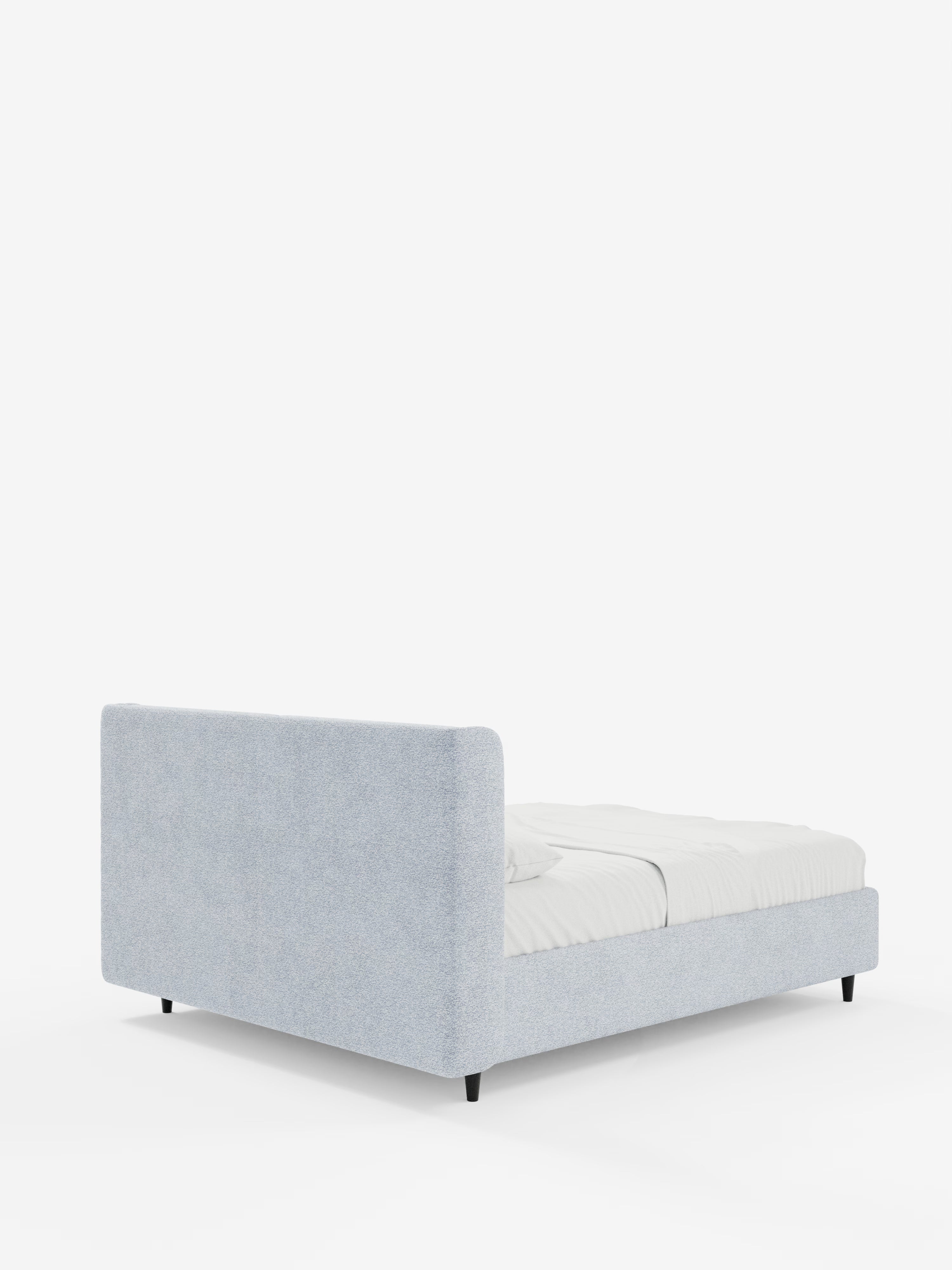 Una vista posteriore mostra il letto di design VALKIRIA con contenitore e testiera avvolgente di Letti.store, caratterizzato da un rivestimento grigio chiaro, gambe corte nere e una testiera rettangolare alta con due cuscini imbottiti in tessuto Oeko-Tex®. Questo letto contemporaneo dal profilo ribassato è abbinato a una biancheria da letto bianca disposta con cura su uno sfondo bianco.