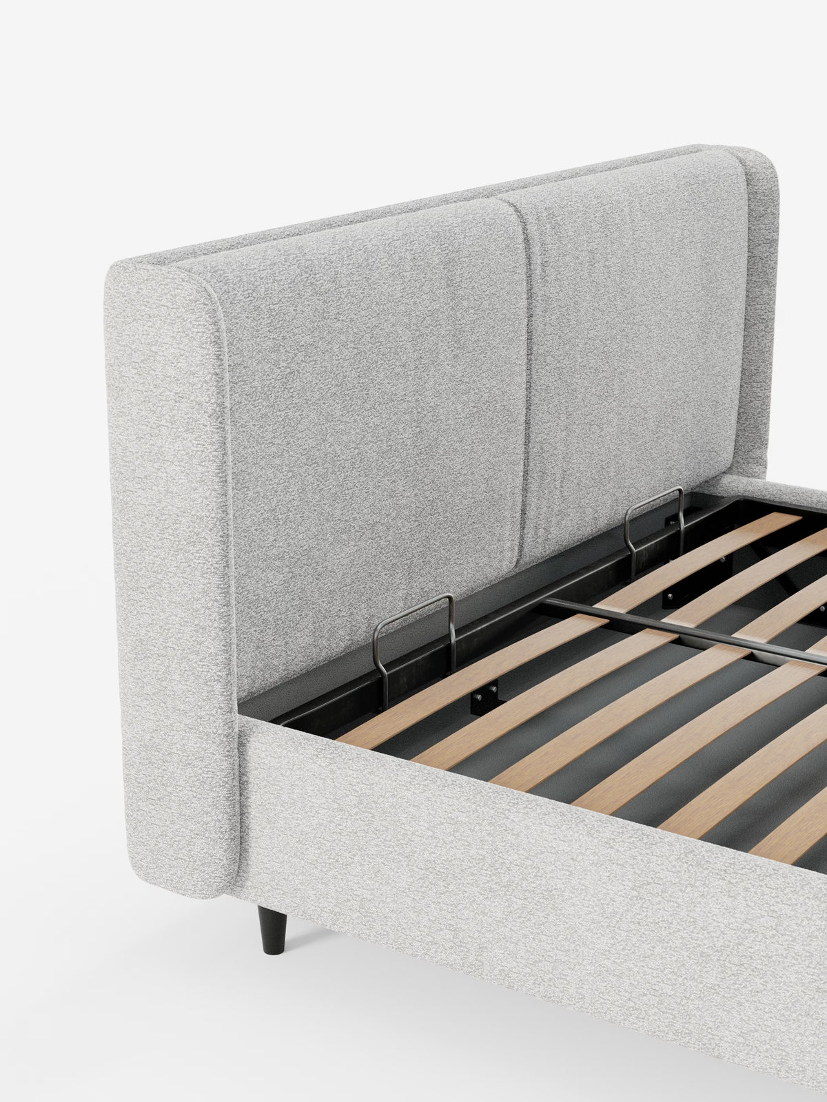 Un primo piano del letto di design VALKIRIA con vano contenitore e testiera avvolgente di Letti.store ne mette in risalto il rivestimento in tessuto grigio chiaro certificato Oeko-Tex® e i due cuscini imbottiti sulla testiera. Sono visibili la robusta struttura in metallo nero e le doghe in legno che sostengono il materasso, con brevi piedini neri che accentuano gli angoli del letto. Sullo sfondo bianco, l’aspetto complessivo ne sottolinea il design contemporaneo e la pratica soluzione di contenimento