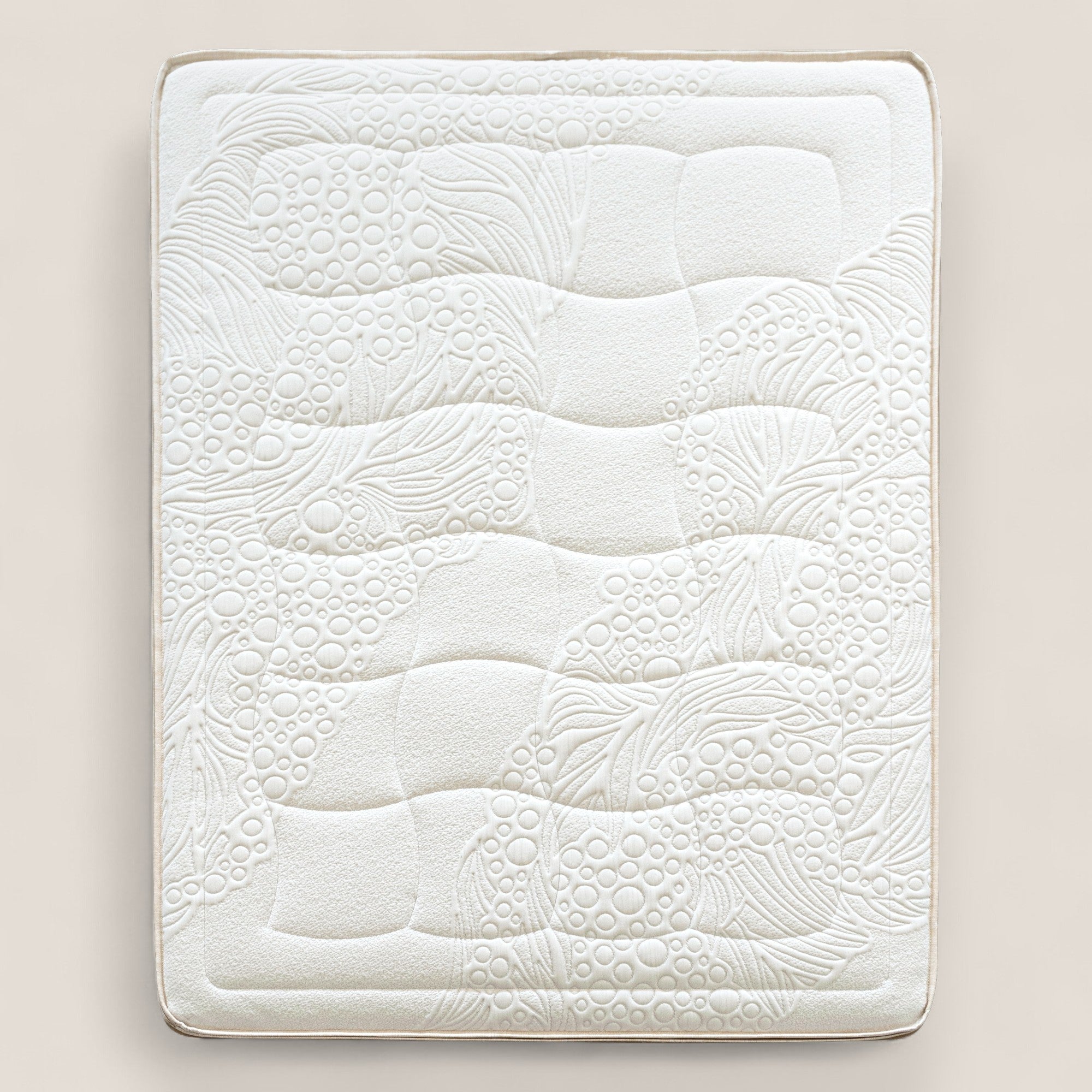 Il materasso VELTHA di Divani.Store è un materasso bioadattivo rettangolare bianco con molle insacchettate a 7 zone e lattice naturale. Presenta una superficie trapuntata e soffice, con linee ondulate e bolle in rilievo, adagiata su un fondo beige chiaro con bordi ordinati.