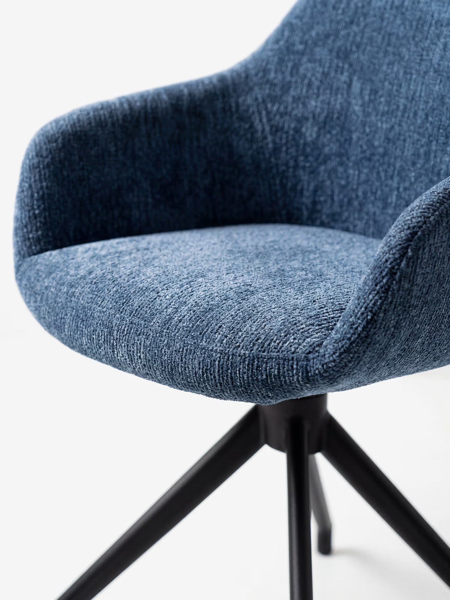 Primo piano della sedia imbottita Vico di Divani.Store, realizzata in morbido tessuto soft-touch certificato OEKO-TEX® con braccioli ricurvi e gambe angolate in metallo nero, che ne esaltano il design contemporaneo su uno sfondo bianco.