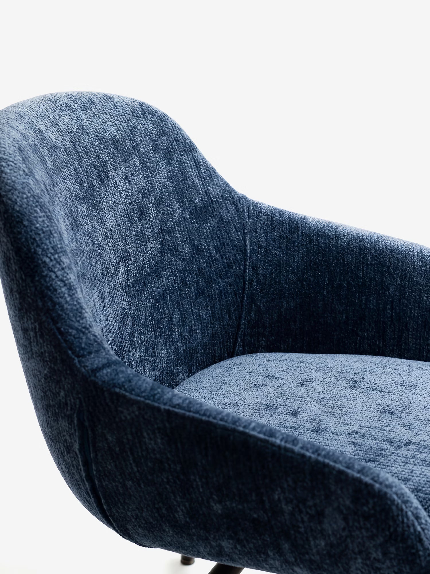 Primo piano della sedia imbottita Vico di Divani.Store, caratterizzata da un tessuto blu morbido al tatto certificato OEKO-TEX®, schienale curvo con braccioli e gambe in metallo nero. La sua silhouette contemporanea risalta su uno sfondo bianco a tinta unita.