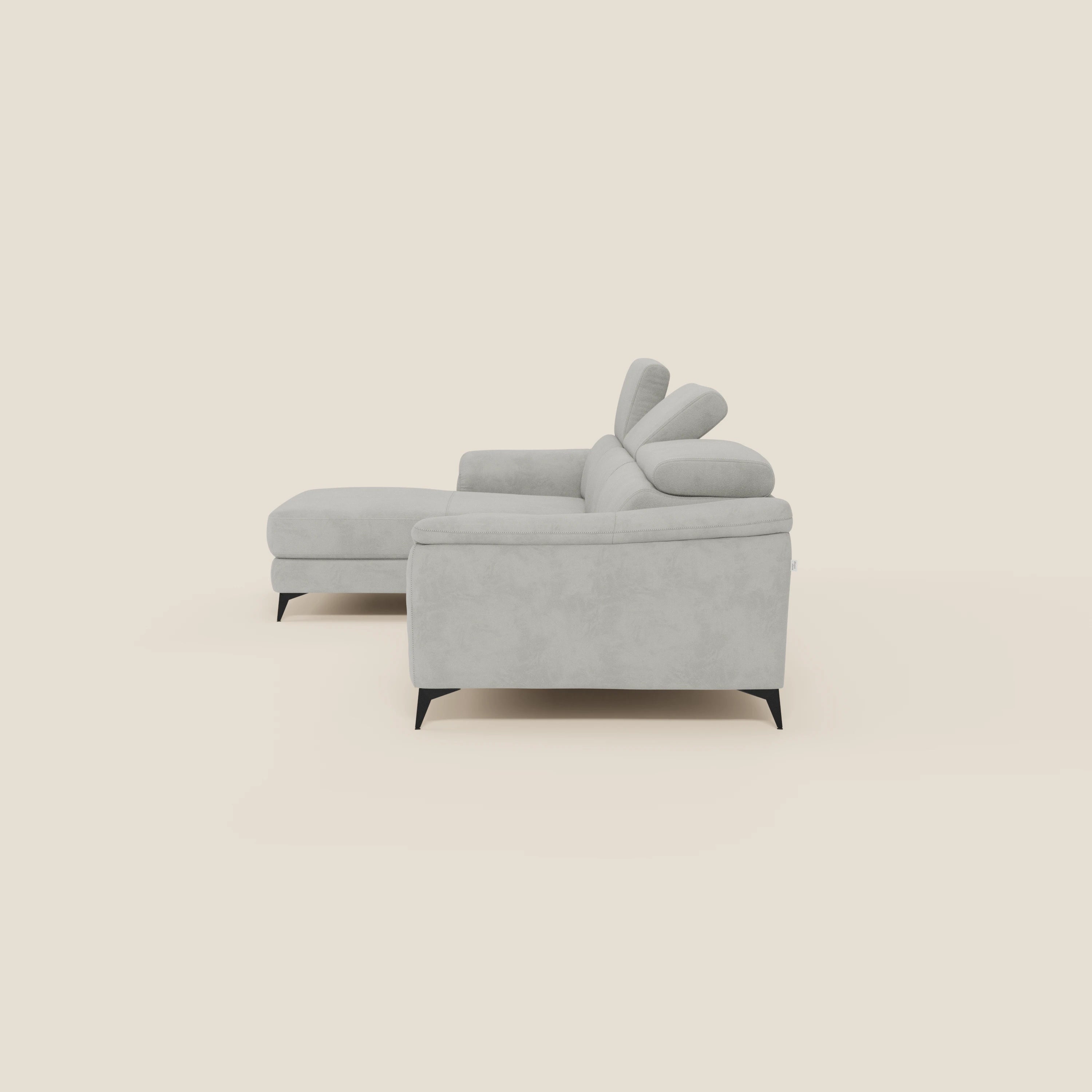 L'Arcos Divano con penisola di Divani.Store è caratterizzato da gambe alte, poggiatesta reclinabili e microfibra impermeabile grigio chiaro T11, su sfondo bianco sporco.