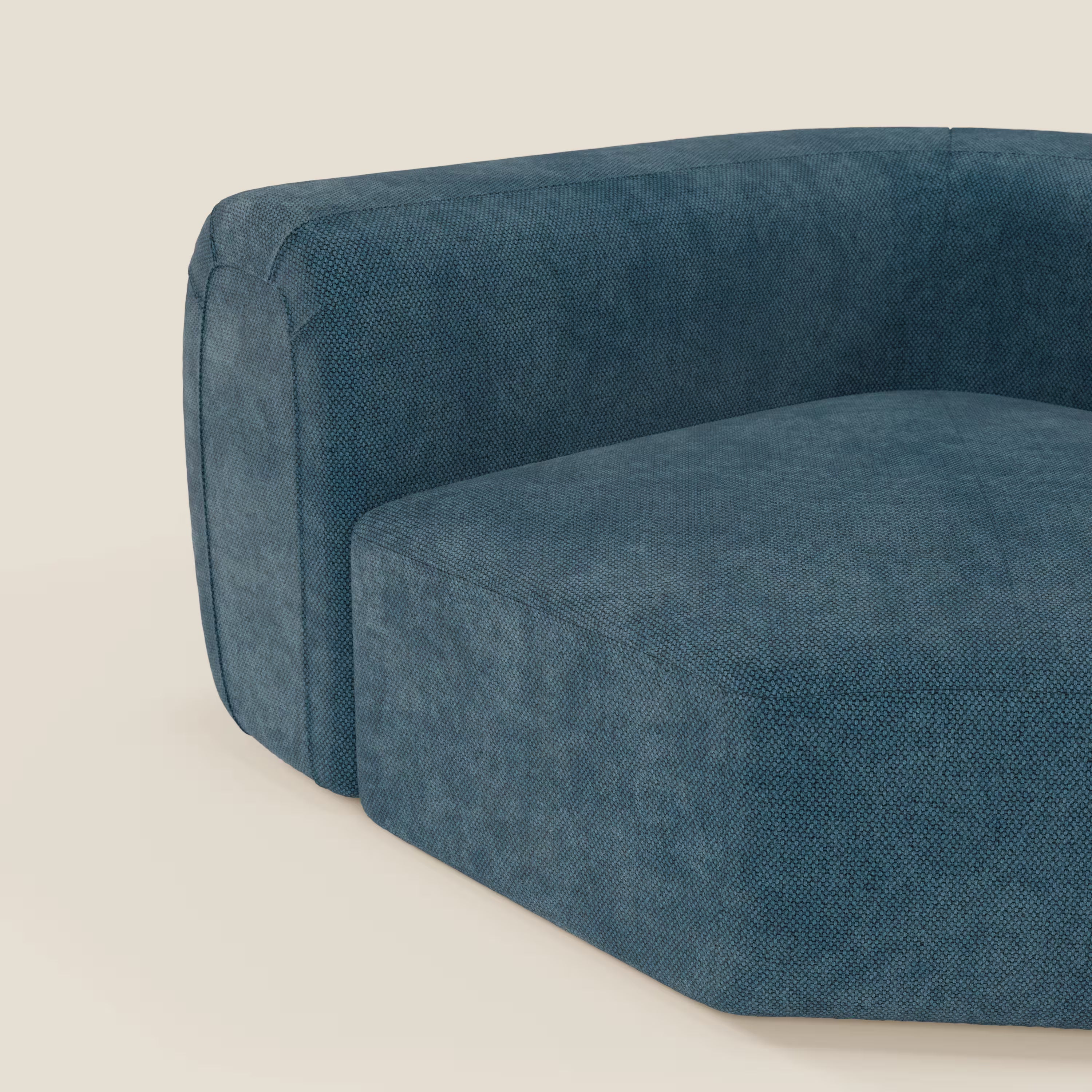 Primo piano del BonBon Modulo angolare - Divano modulare componibile GF edition petrolio di Divani.Store, caratterizzato da un tessuto strutturato blu intenso e da braccioli e sedile dal design squadrato su uno sfondo beige chiaro.