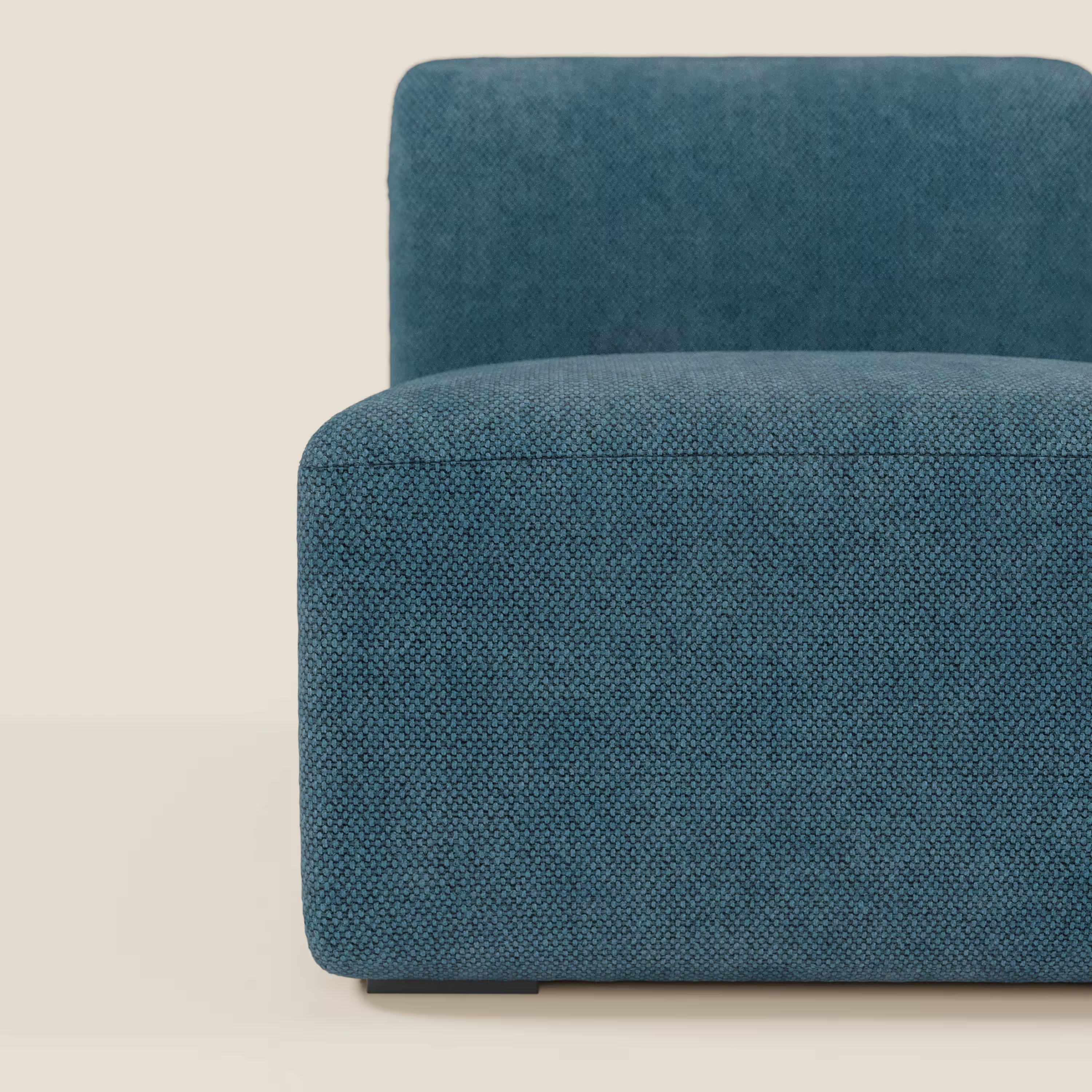 Un primo piano del BonBon modulo centrale 70 cm - Grande Fratello edition petrolio di Divani.Store, che mostra la sua forma squadrata e minimalista e il rivestimento blu testurizzato: solo il lato sinistro appare su uno sfondo chiaro.