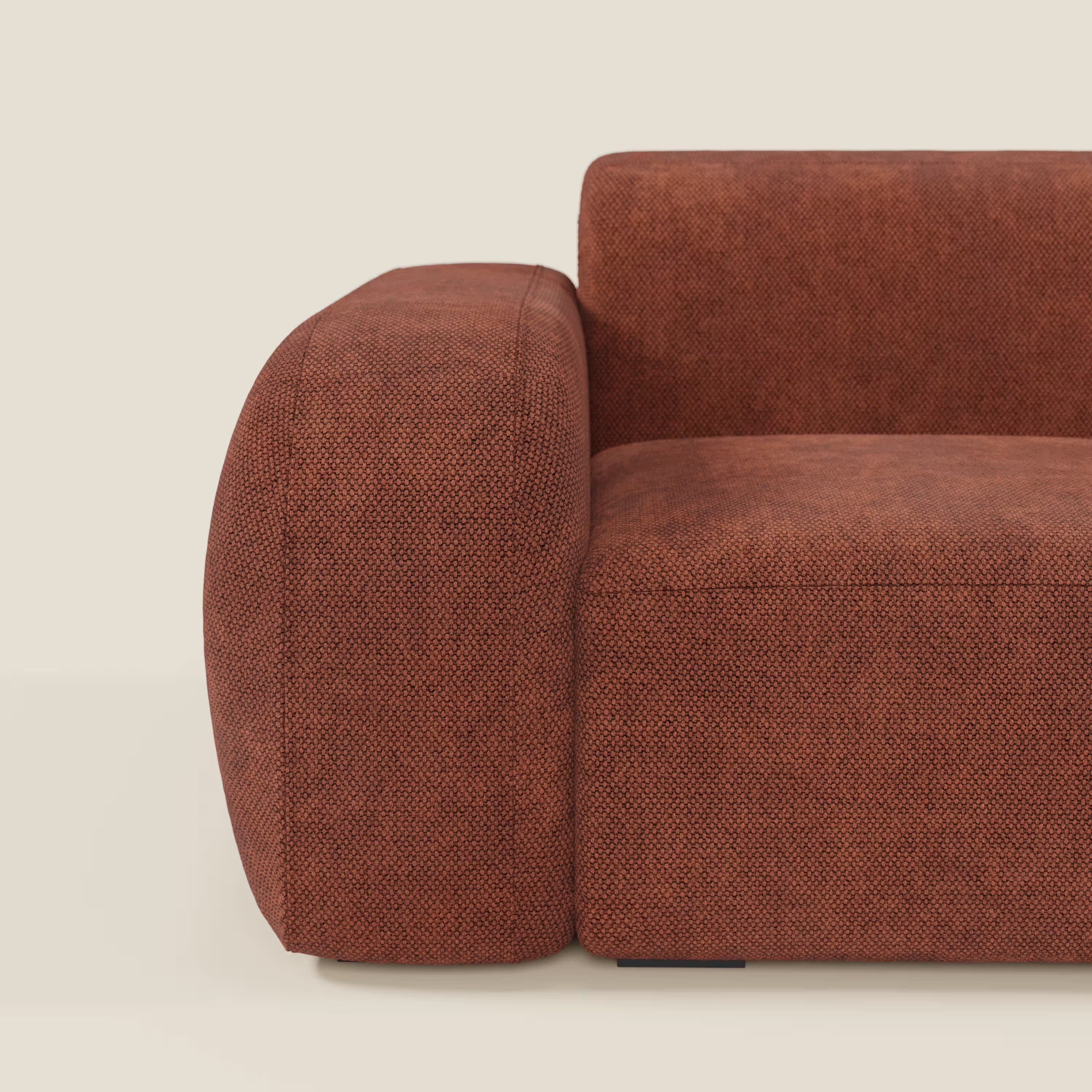 Un primo piano del tappeto BonBon modulo terminale 105 cm sinistro o destro - Grande Fratello edition di Divani.Store mette in evidenza il suo tessuto strutturato arancione bruciato, i bordi arrotondati e l'elegante design modulare su uno sfondo bianco sporco.