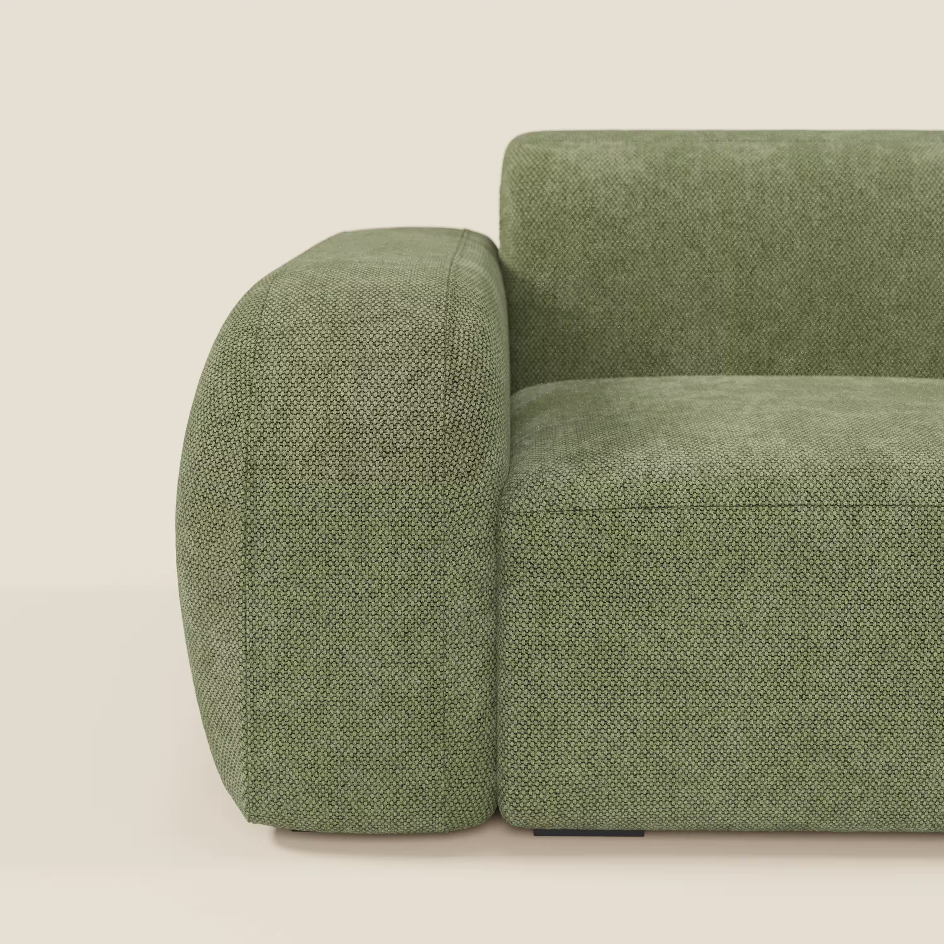 Primo piano del lato sinistro del BonBon modulo terminale 105 cm sinistro - Grande Fratello edition verde muschio di Divani.Store, caratterizzato da un bracciolo arrotondato e sovradimensionato e da un cuscino in tessuto verde testurizzato. Prodotto in Italia.