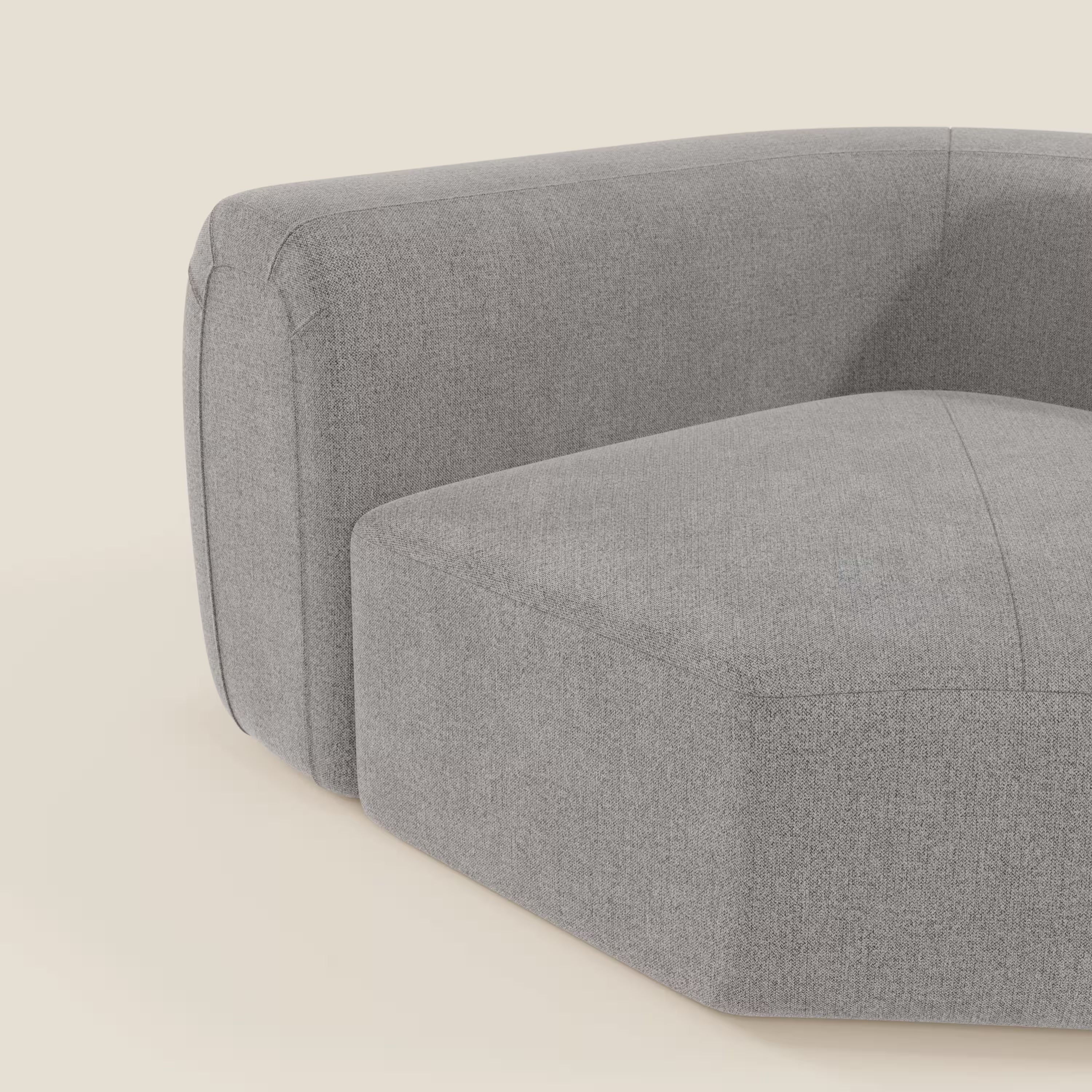 Primo piano di Bonbon Modulo angolare di Divani.Store, un moderno divano modulare grigio in tessuto smacchiabile T23 con seduta bassa e ampia e braccioli spessi e arrotondati su uno sfondo beige chiaro. Il tessuto liscio e le cuciture sottili completano il look.