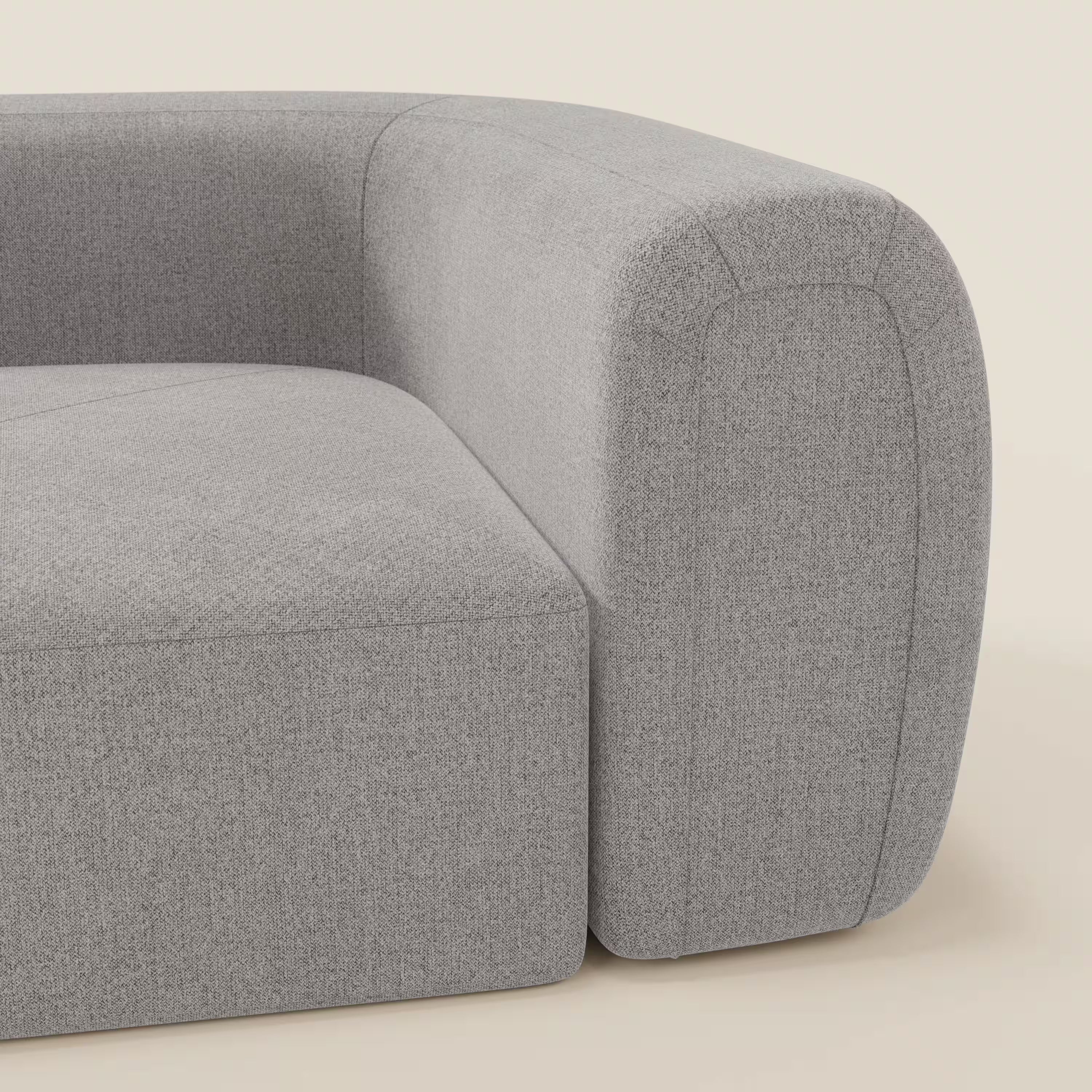 Primo piano di Bonbon Modulo angolare di Divani.Store, un moderno divano modulare grigio chiaro rivestito in tessuto antimacchia T23, caratterizzato da un bracciolo curvo e da sottili cuciture su uno sfondo beige neutro.