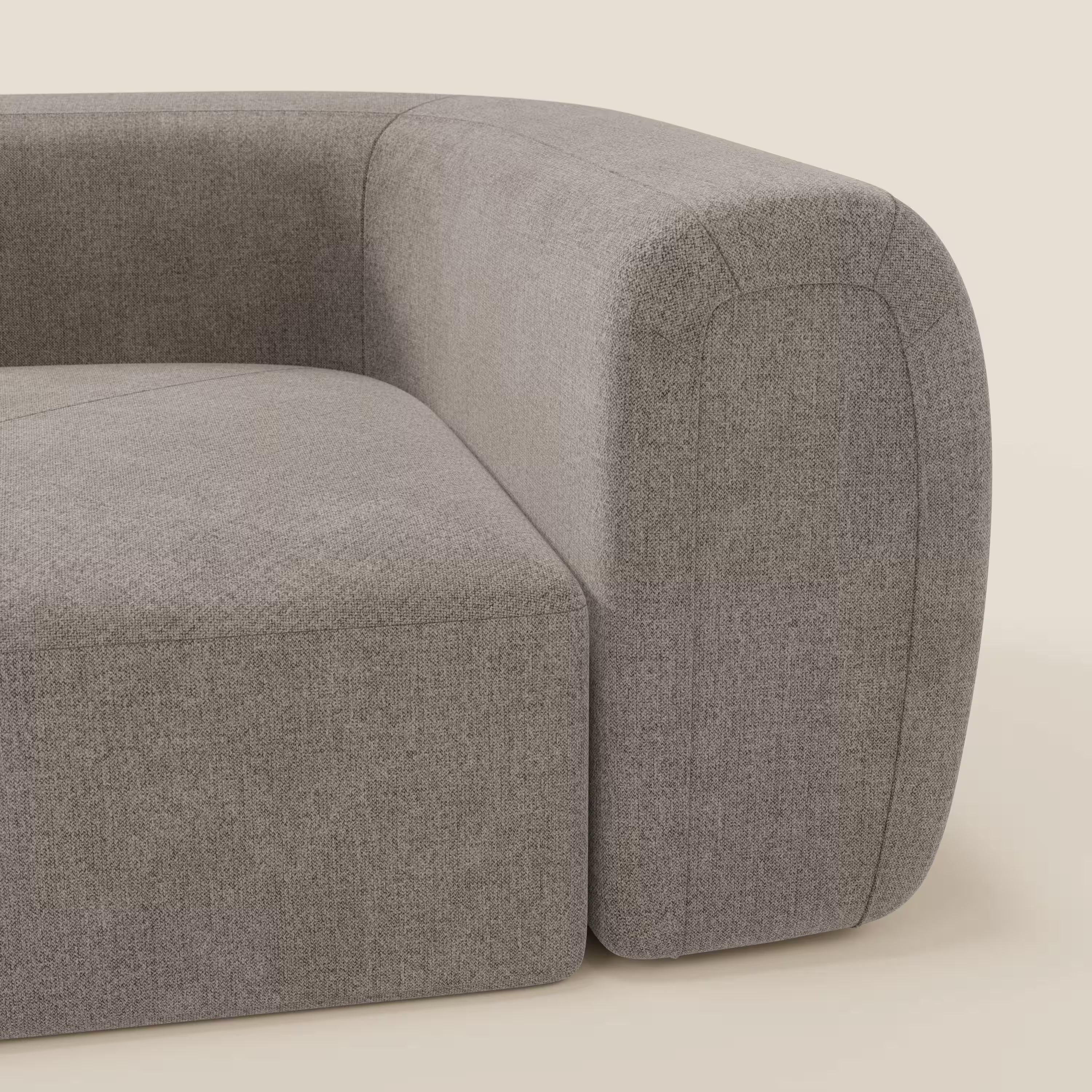 Un primo piano del Bonbon Modulo angolare di Divani.Store mostra il morbido tessuto antimacchia T23 talpa, i bordi arrotondati e gli spessi braccioli. Lo sfondo beige semplice mette in risalto l'eleganza del design e la consistenza di questo divano moderno e modulare.