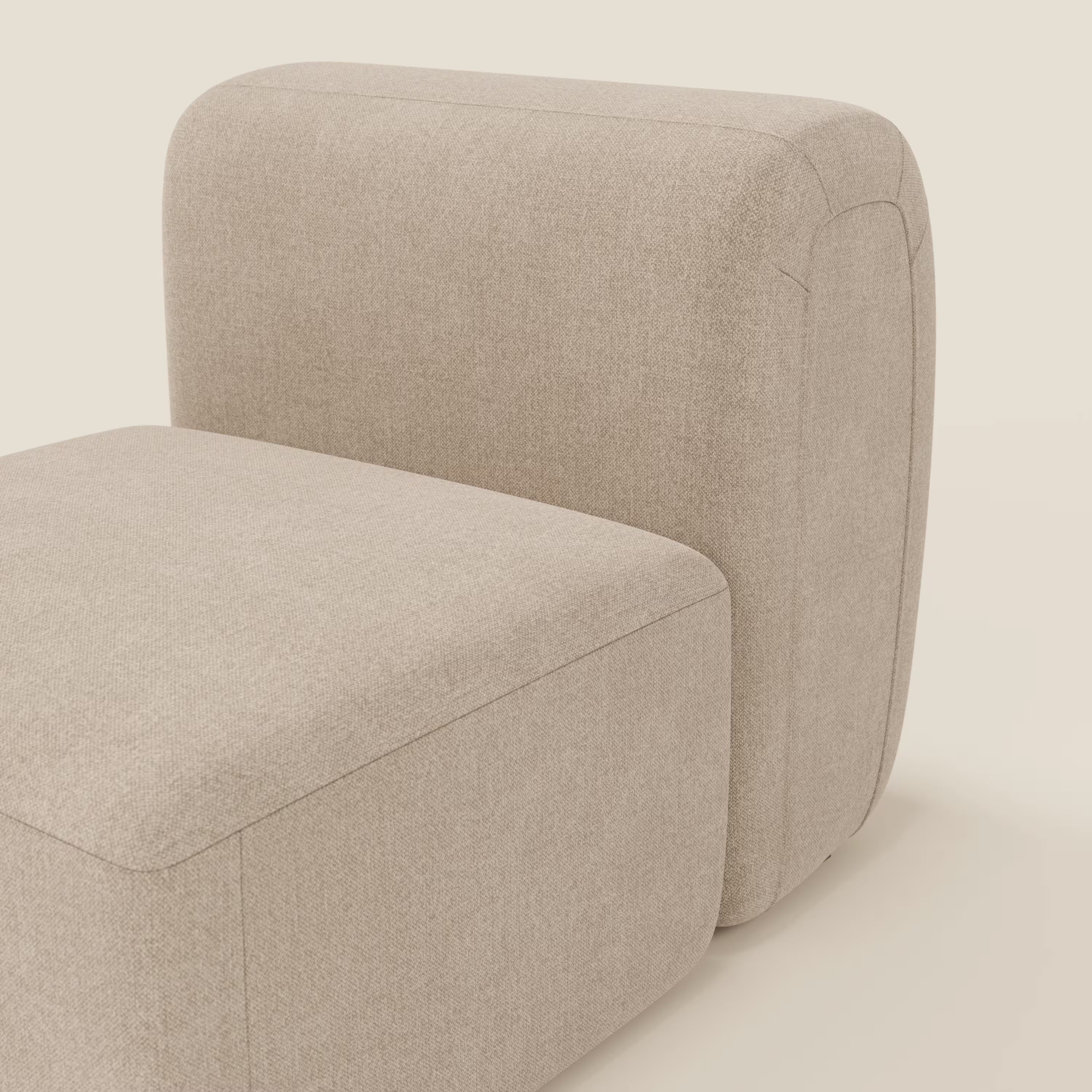 Primo piano di BonBon modulo centrale 70 cm di Divani.Store, una poltrona lounge senza braccioli e di forma squadrata in tessuto antimacchia T23 beige con bordi arrotondati e cuciture a vista, su uno sfondo bianco sporco.