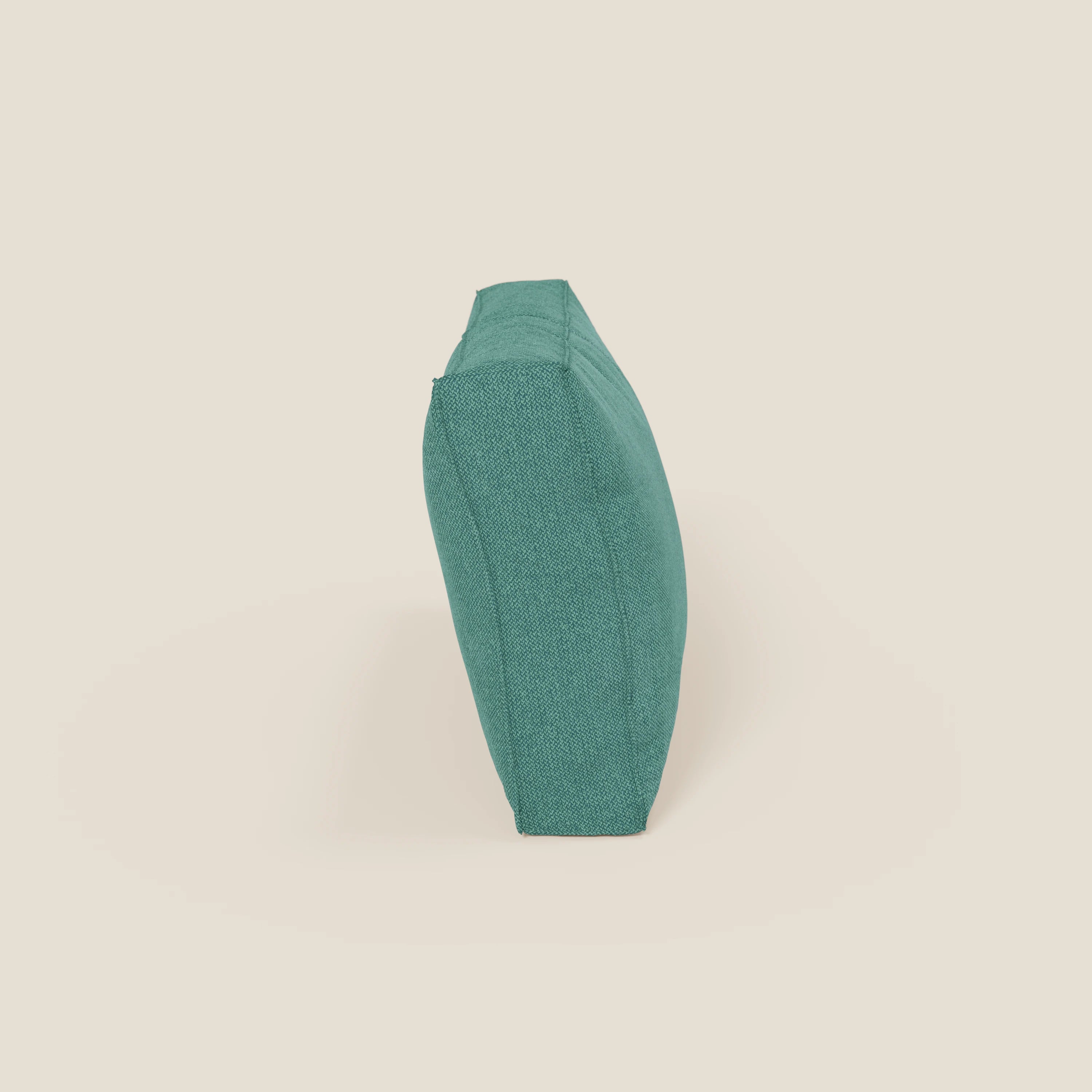 Un cuscino schienale BonBon di Divani.Store, raffigurato di profilo su uno sfondo beige chiaro, è caratterizzato da un tessuto smacchiabile T23 verde acqua, da bordi netti e da un aspetto grassoccio con il lato stretto rivolto verso l'osservatore.