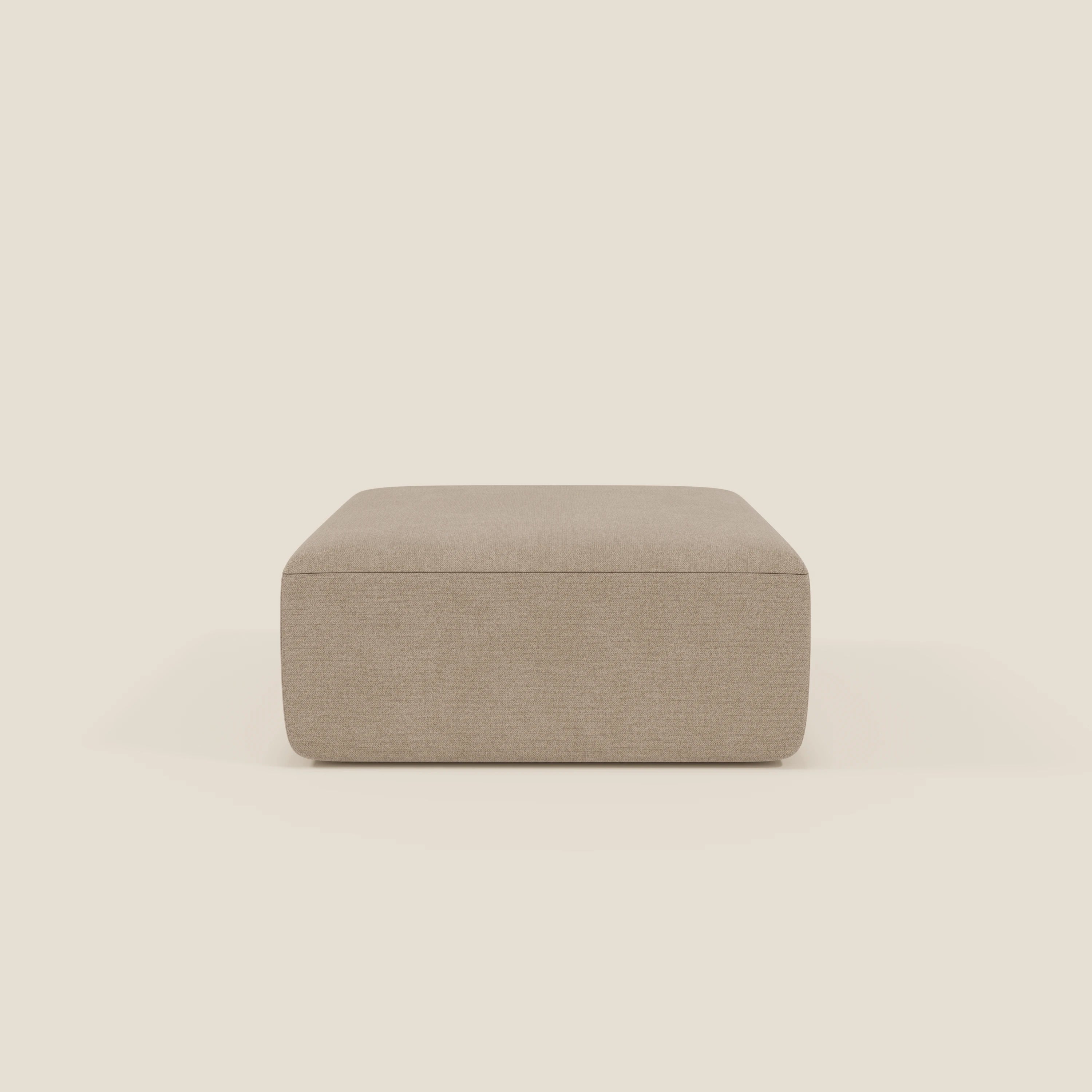 Il pouf divano modulare BonBon di Divani.Store, qui presentato in tessuto antimacchia T23 beige, è caratterizzato da un semplice design rettangolare senza gambe o decorazioni per un look minimalista e moderno su uno sfondo crema chiaro.