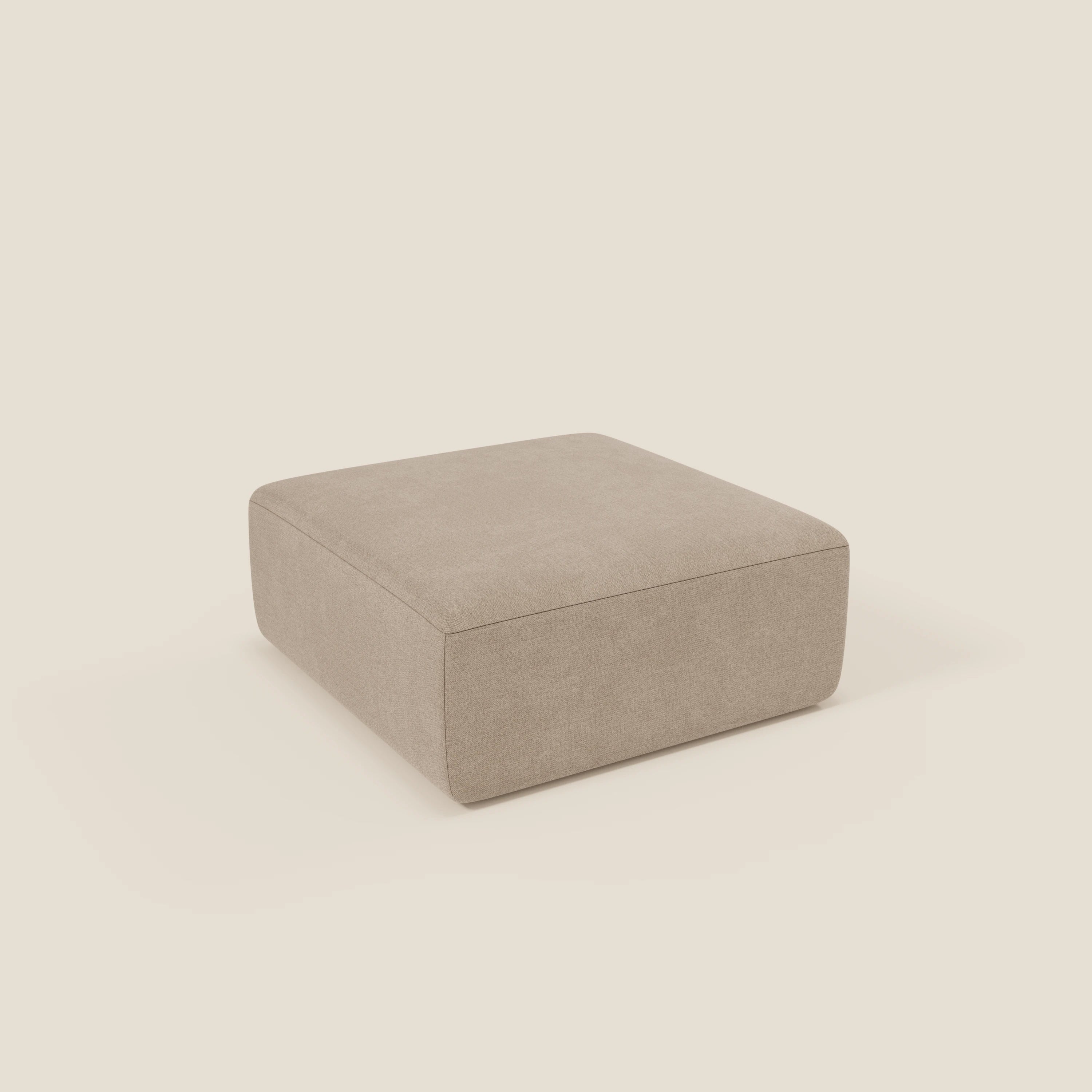 Il pouf BonBon di Divani.Store è un pouf quadrato di colore beige in tessuto antimacchia T23, dalle linee pulite e senza gambe visibili, presentato su uno sfondo bianco sporco. Disponibile in due dimensioni modulari.