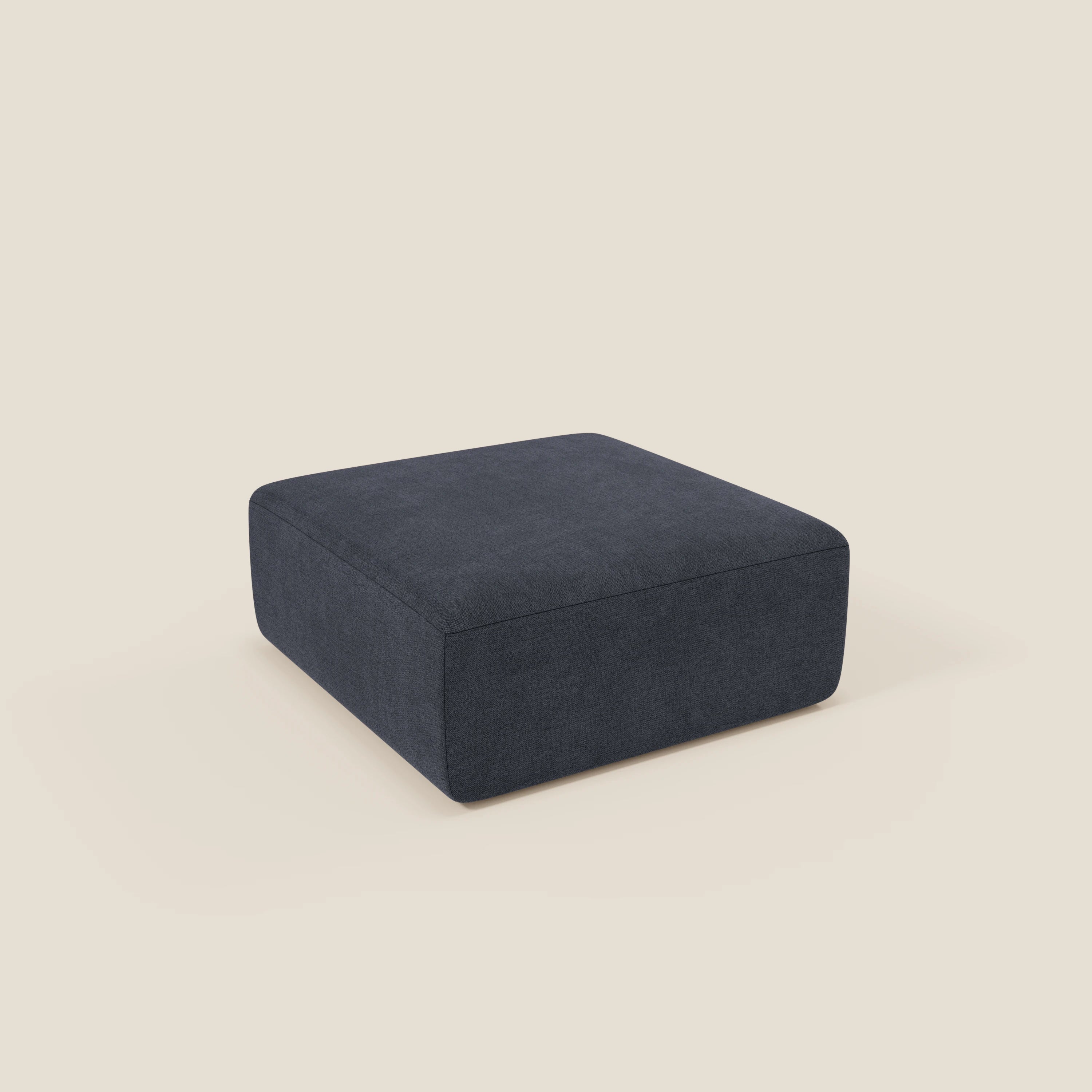 Il pouf BonBon di Divani.Store, in tessuto smacchiabile T23 blu ardesia, è caratterizzato da una forma squadrata, linee pulite, profilo basso e design minimalista. Si colloca su uno sfondo beige chiaro, senza gambe o abbellimenti visibili.