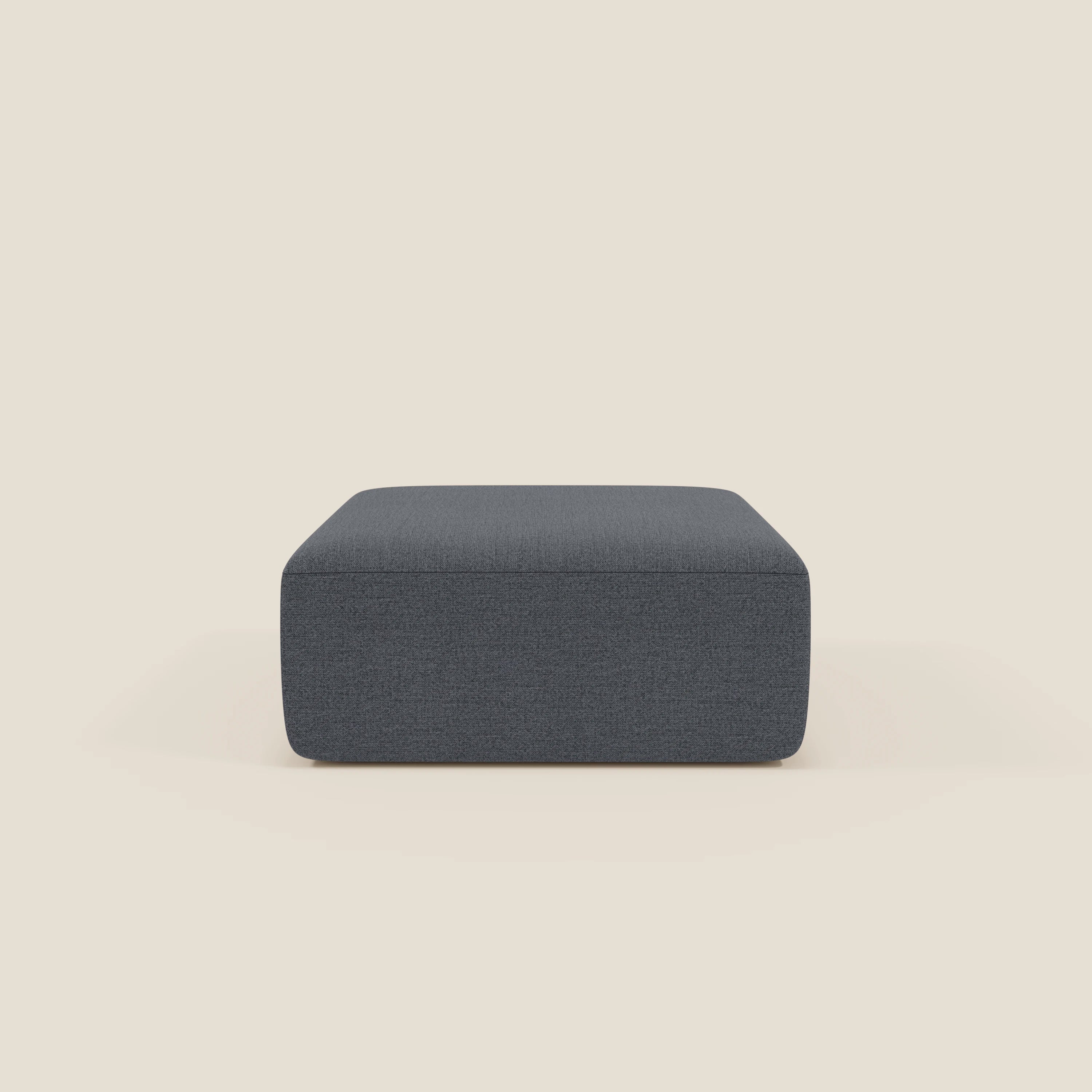 Il pouf divano modulare BonBon di Divani.Store in tessuto antimacchia T23 blu grafite è rettangolare con una morbida imbottitura, linee pulite e un design semplice e moderno, centrato su uno sfondo beige chiaro. Non ci sono gambe o abbellimenti visibili.