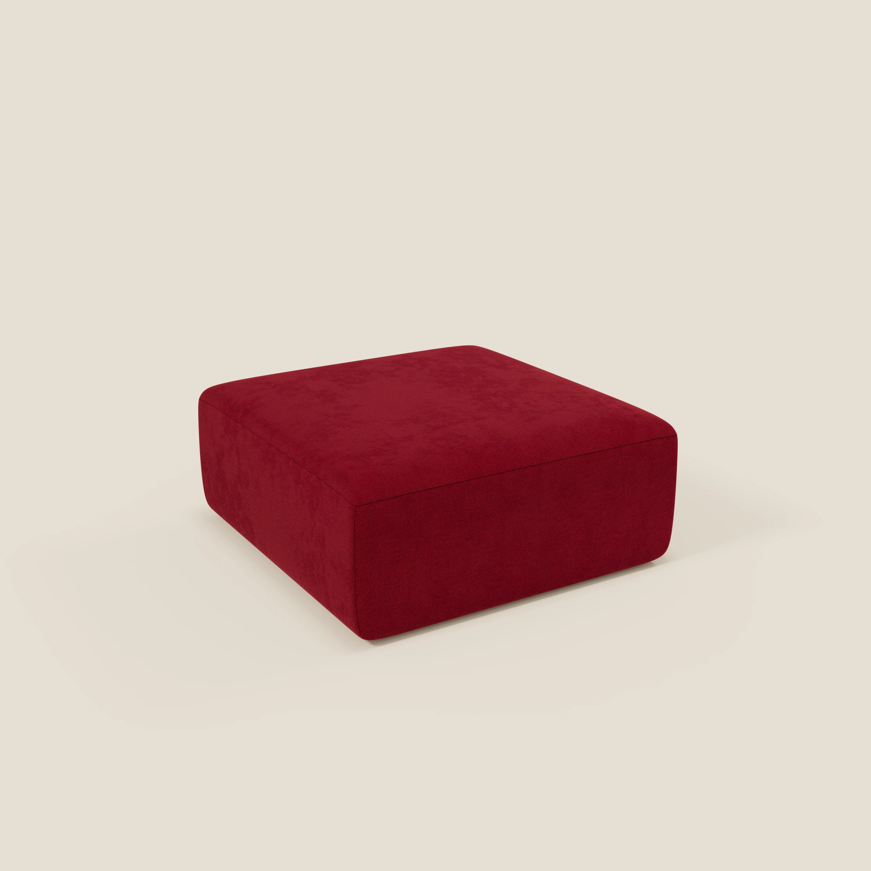 Il pouf divano modulare BonBon di Divani.Store, di grandi dimensioni e in tessuto antimacchia T23 bordeaux, è caratterizzato da un design squadrato e minimalista, con linee pulite e assenza di gambe visibili, su uno sfondo beige chiaro.