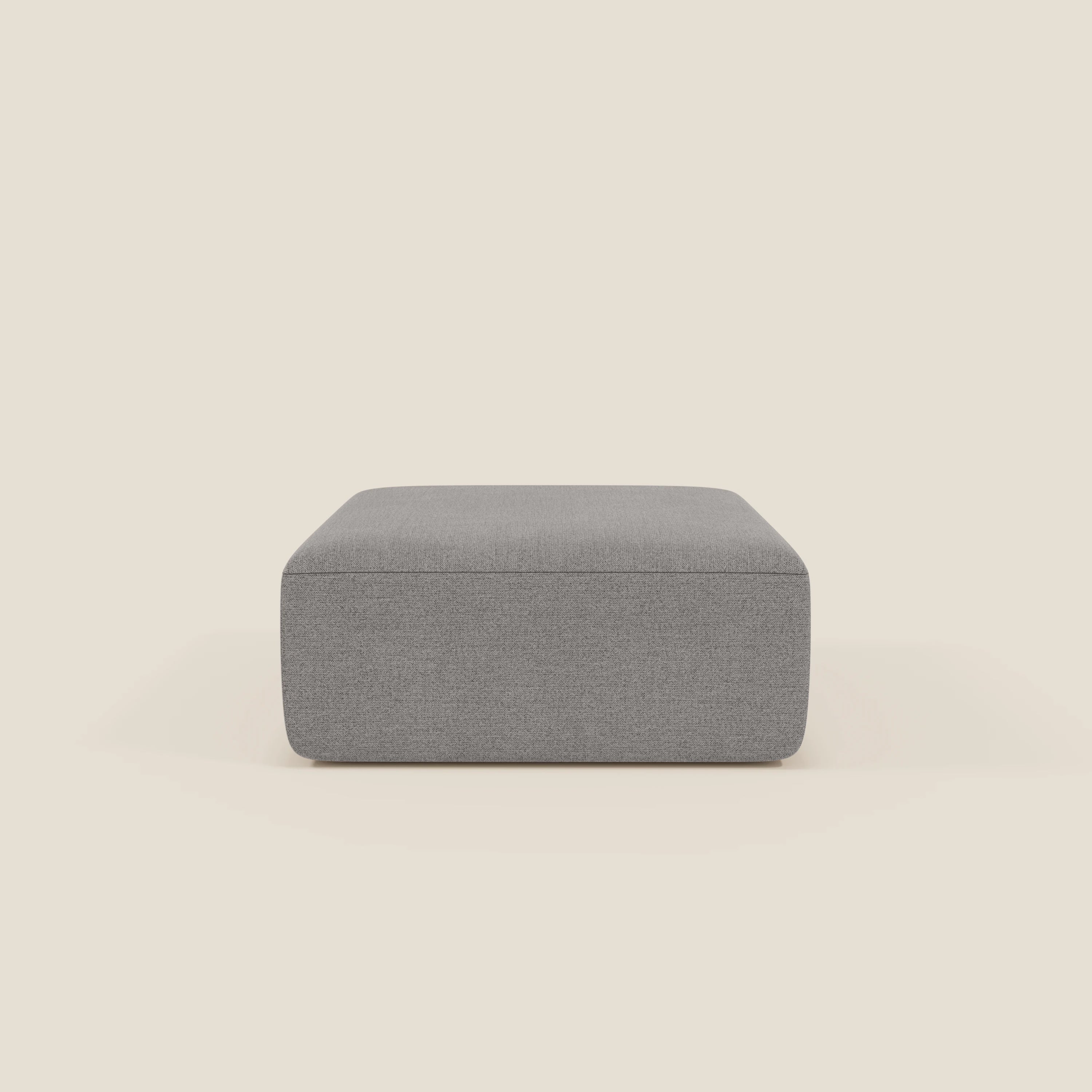 Il pouf divano modulare BonBon di Divani.Store, qui presentato in tessuto antimacchia T23 grigio, ha un design moderno e rettangolare con linee pulite e un profilo basso. È posizionato su uno sfondo beige chiaro per un look minimalista.
