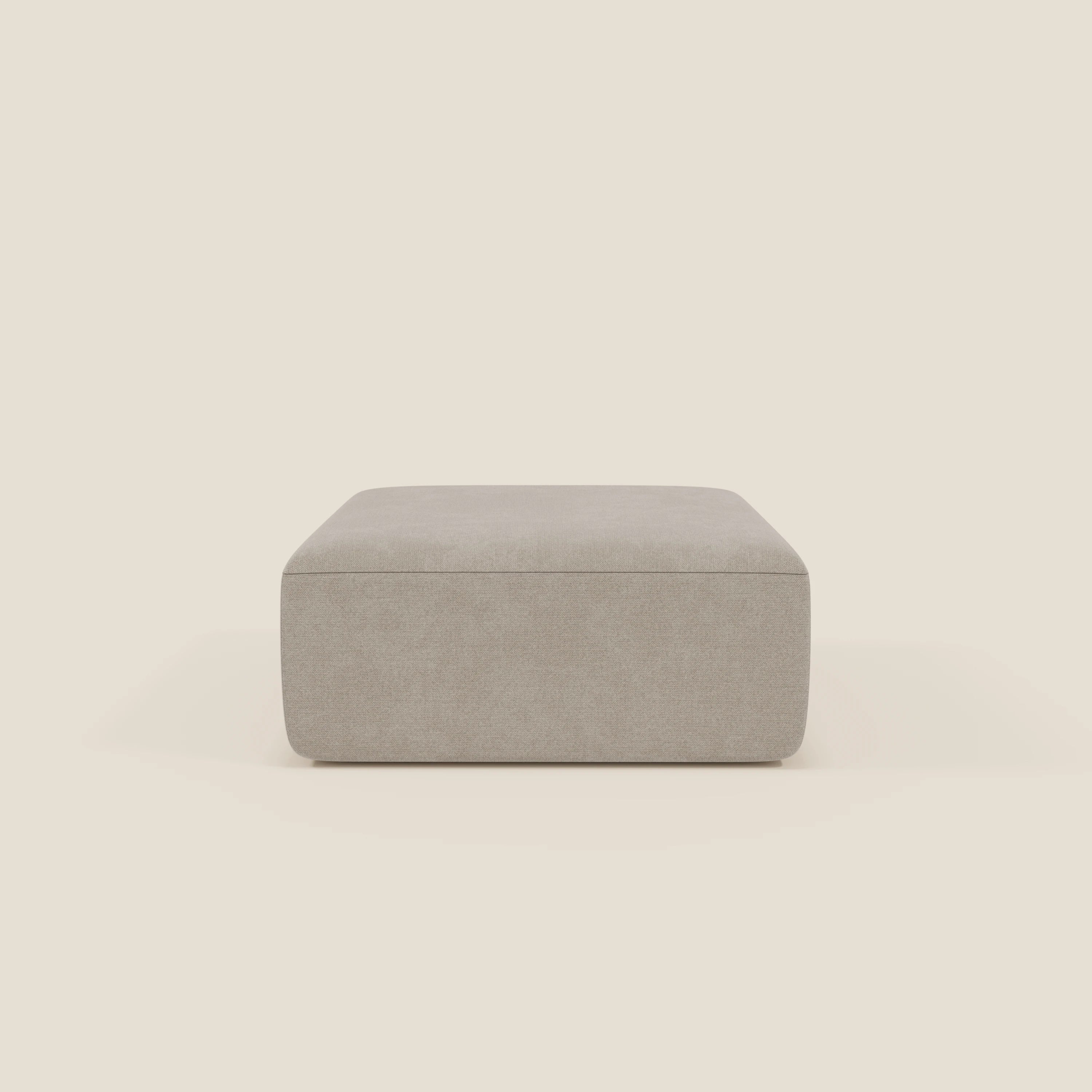 Il pouf divano modulare BonBon di Divani.Store, qui presentato in tessuto smacchiabile T23 panna, è caratterizzato da un design quadrato minimalista con bordi morbidi e finitura liscia, centrato su uno sfondo bianco sporco per un look moderno.