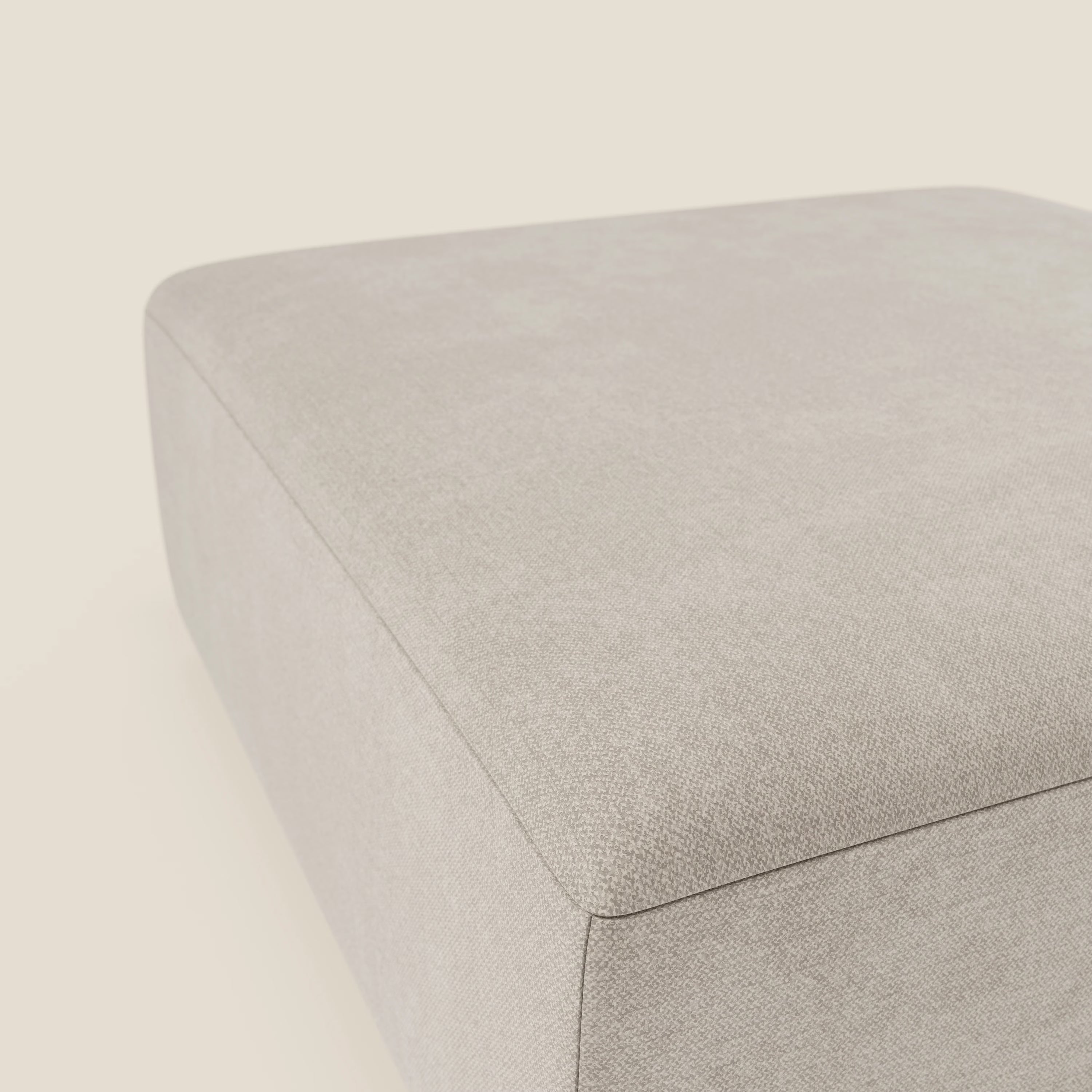 Primo piano del pouf divano modulare BonBon di Divani.Store in tessuto smacchiabile T23 panna. La tonalità beige chiaro e la superficie strutturata creano un look minimalista e moderno con uno sfondo neutro abbinato. Disponibile in 2 misure.