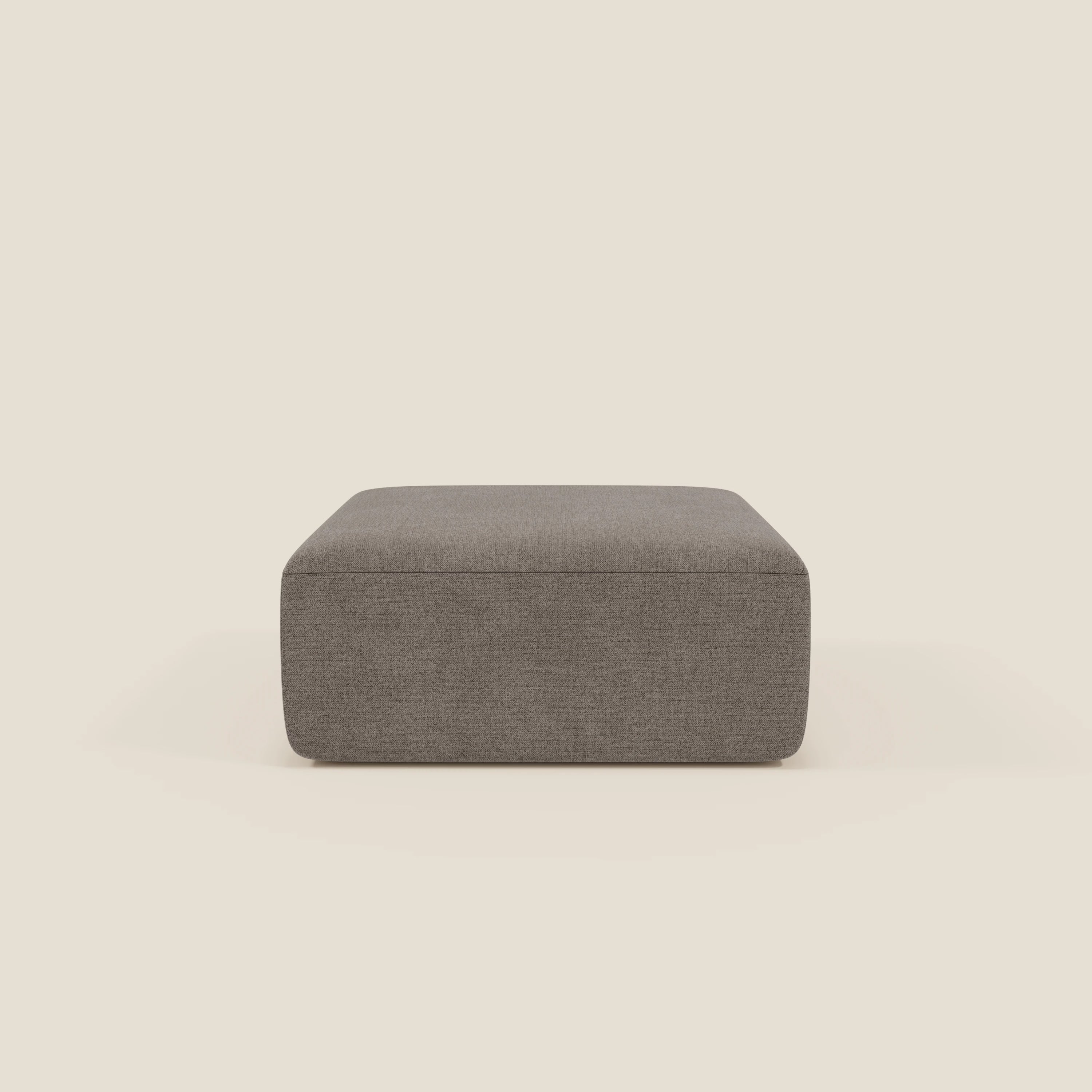Il pouf modulare BonBon di Divani.Store, realizzato in tessuto antimacchia T23 taupe, è centrato su uno sfondo beige chiaro, caratterizzato da linee pulite, un design moderno e squadrato, senza gambe o abbellimenti visibili.