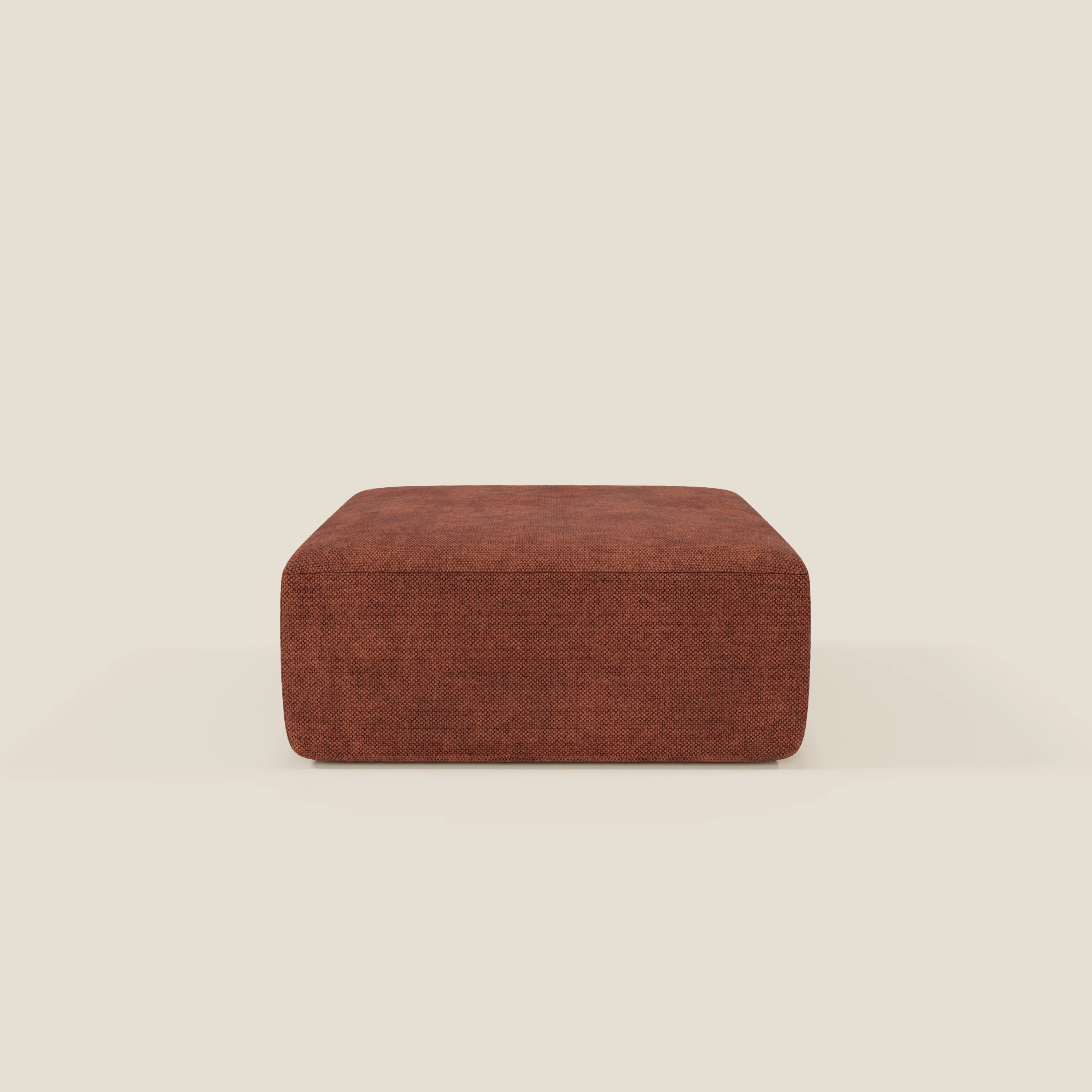 Il pouf BonBon modulo Grande Fratello edition ruggine di Divani.Store è un pouf quadrato a basso profilo, in tessuto strutturato color ruggine con bordi arrotondati e lisci, su uno sfondo beige semplice e dal design semplice e moderno.