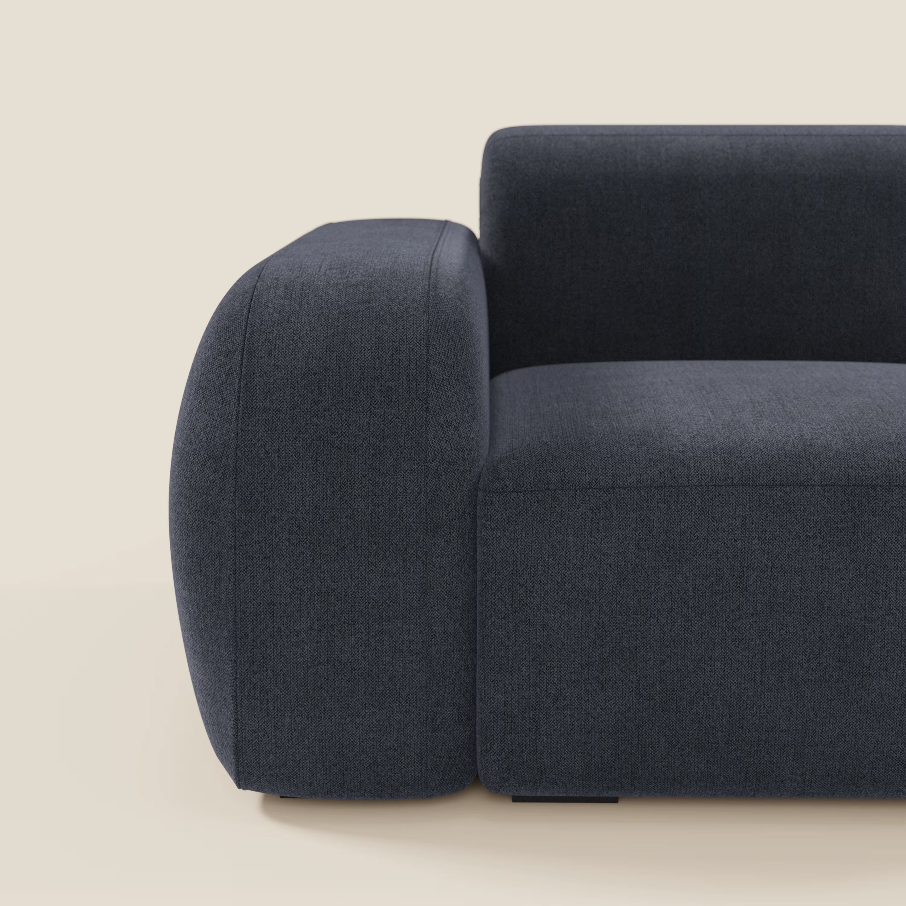 Primo piano del BonBon modulo terminale 105 cm sinistro di Divani.Store in tessuto smacchiabile T23 blu ardesia, ripreso lateralmente con i bracci spessi e arrotondati e le linee minimaliste su uno sfondo beige chiaro. Viene mostrata solo la metà sinistra.