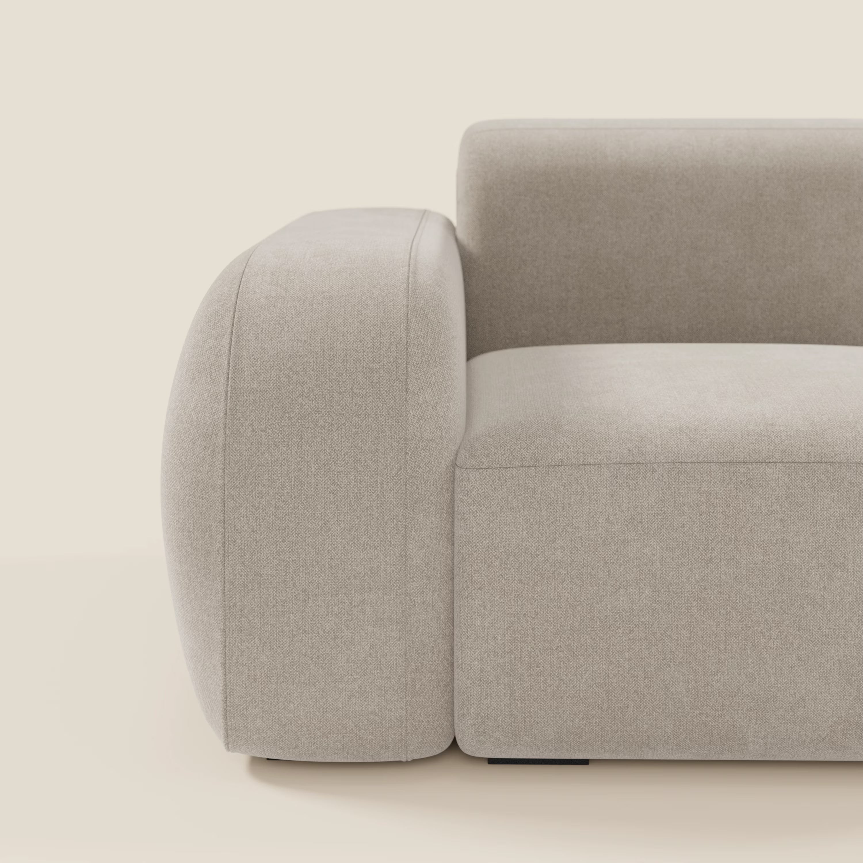 Un primo piano del BonBon modulo terminale 105 cm sinistro o destro di Divani.Store in tessuto smacchiabile T23 panna mette in evidenza l'ampio bracciolo arrotondato e il cuscino di seduta dal design morbido e minimalista su uno sfondo neutro.