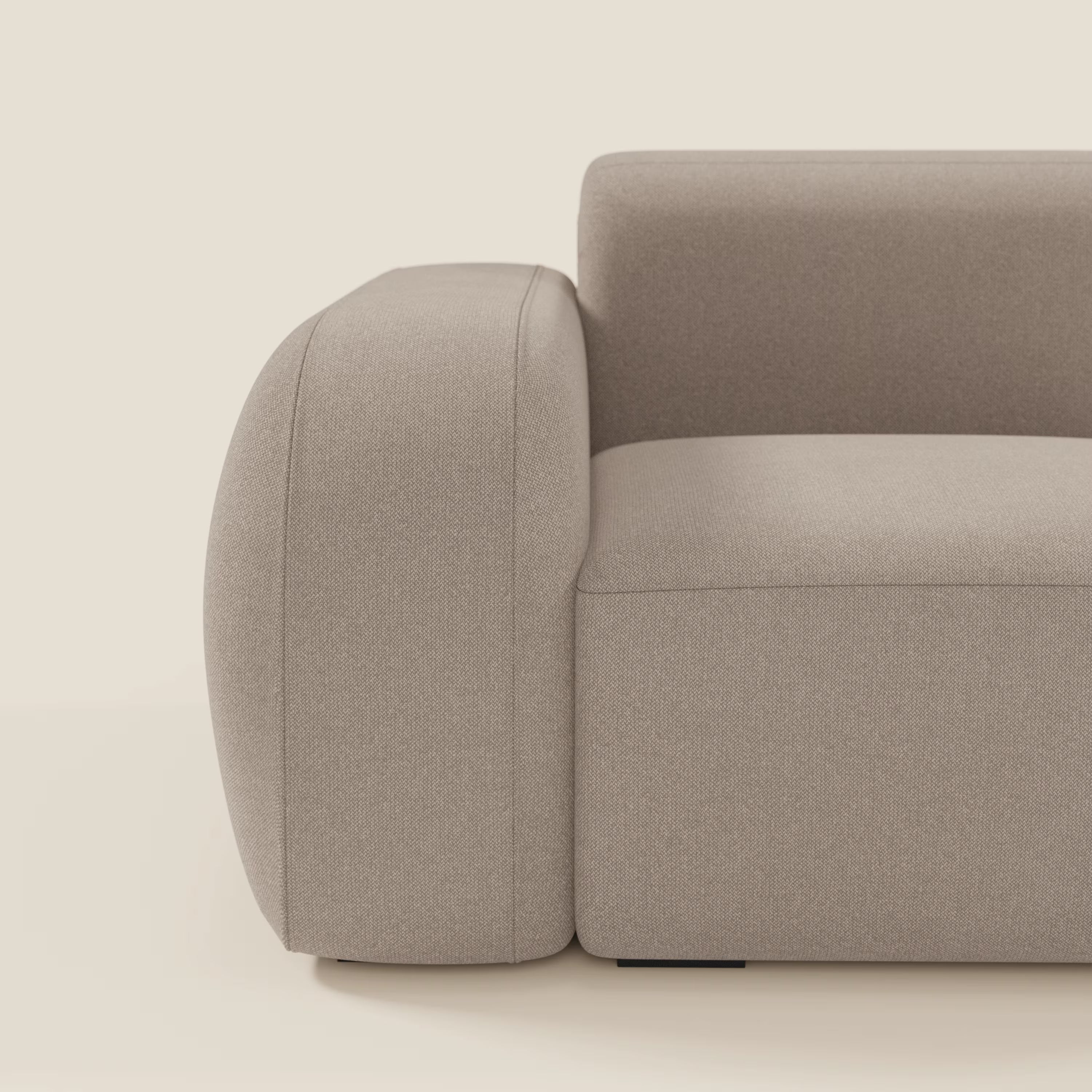 Un primo piano del Divani.Store BonBon modulo terminale 105 cm sinistro o destro in tessuto smacchiabile T23 tortora mostra linee pulite e stile minimal. Il fondo crema chiaro esalta il tono neutro e la consistenza morbida del divano.