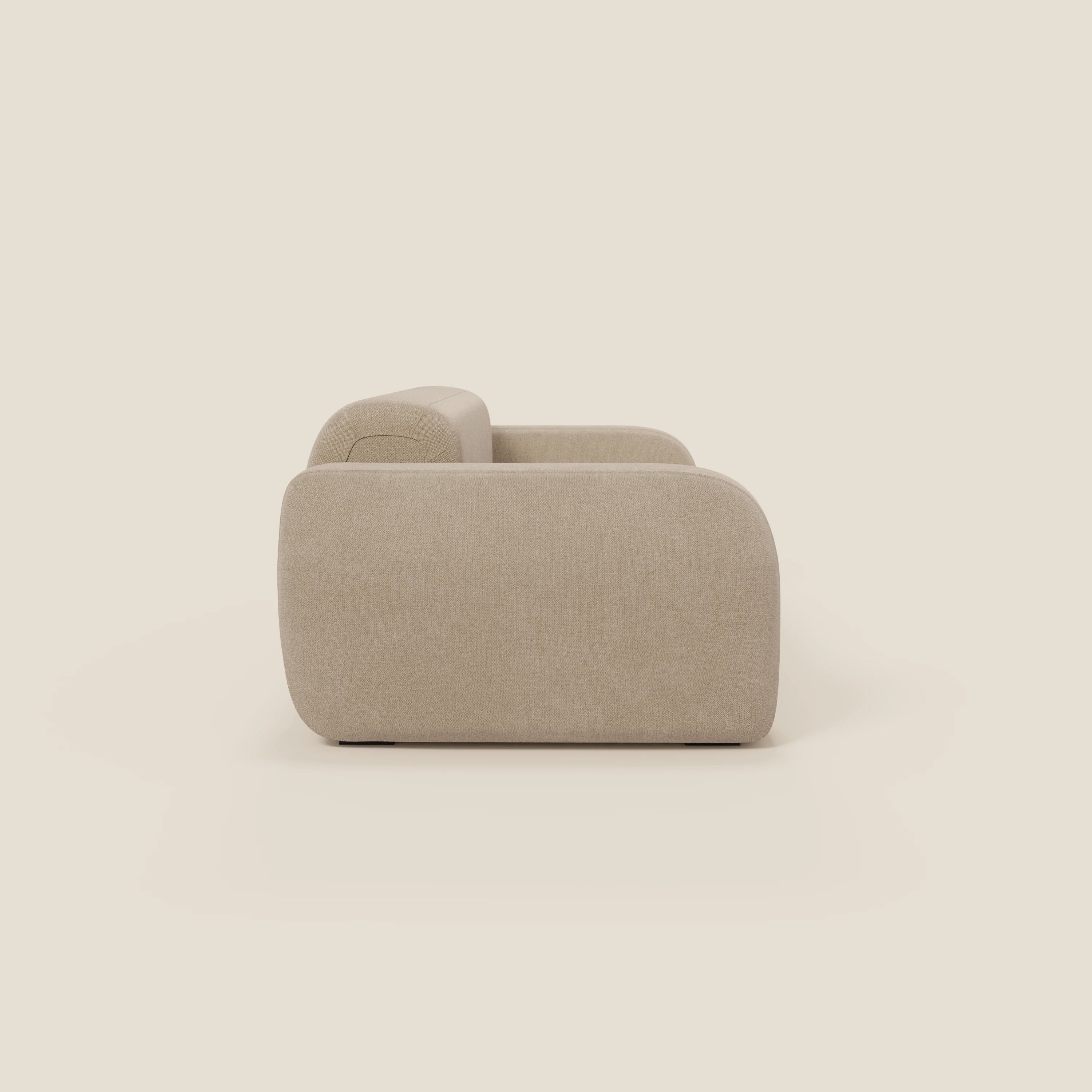 Il BonBon Divano modulare Lineare 220 di Divani.Store è presentato lateralmente su uno sfondo bianco sporco. La seduta unica e il tessuto smacchiabile T23 beige conferiscono a questo divano moderno e compatto dai bordi arrotondati un aspetto morbido e invitante.