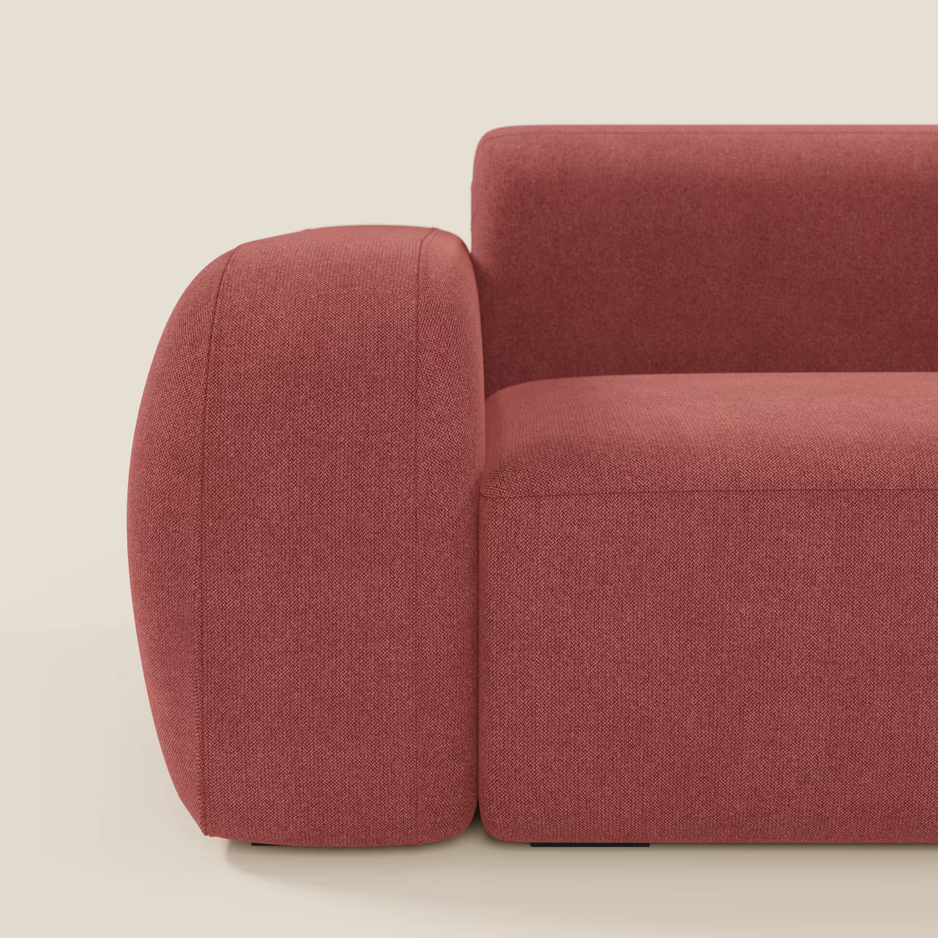 Primo piano del BonBon Divano modulare Lineare 220 di Divani.Store, caratterizzato da un bracciolo arrotondato e da una seduta morbida in tessuto smacchiabile T23 rosso ciliegia. Le linee curve del design contemporaneo spiccano su uno sfondo beige chiaro.