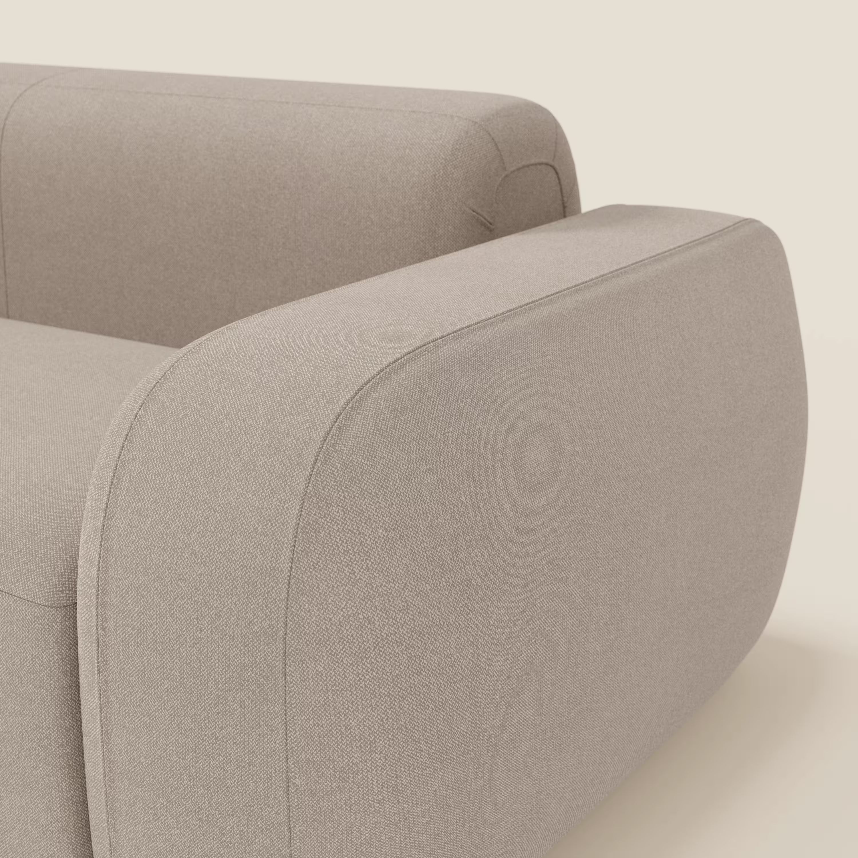 Primo piano di BonBon Divano modulare Lineare 220 di Divani.Store, caratterizzato da un bracciolo spesso e arrotondato con cuciture a vista in tessuto smacchiabile T23 tortora e da un design a seduta unica, su uno sfondo bianco sporco.