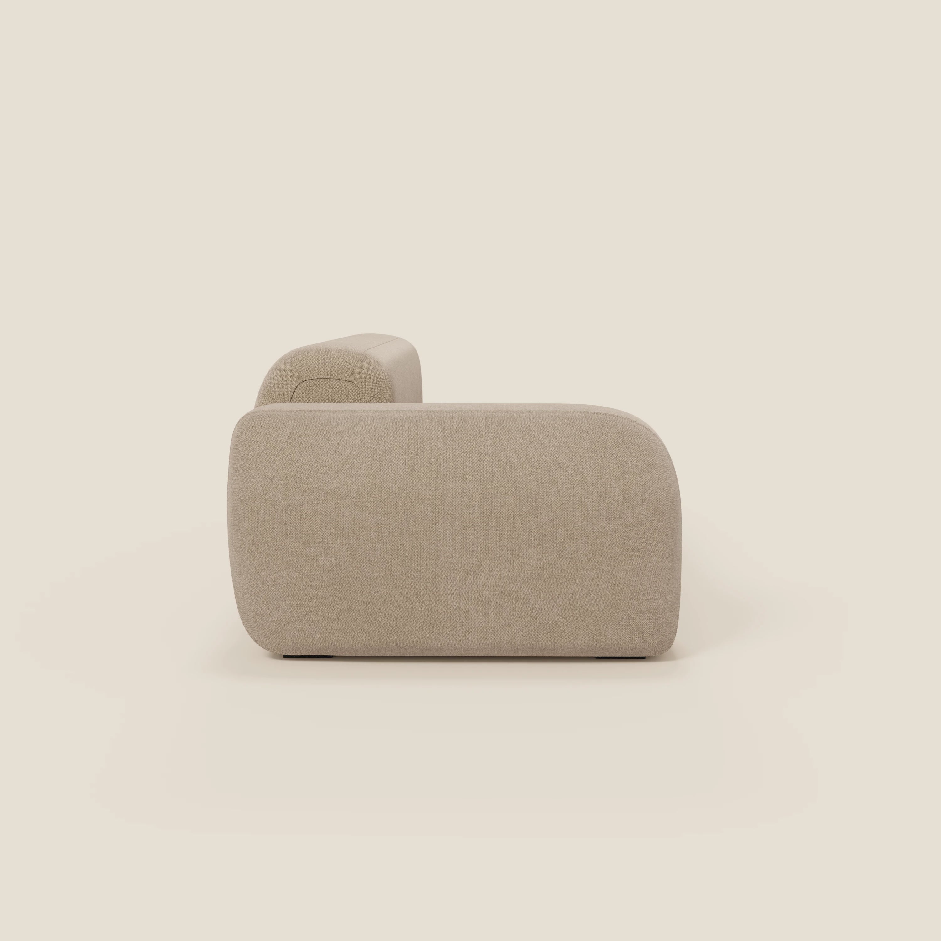 Il BonBon Divano componibile di Divani.Store, in tessuto smacchiabile T23 beige con pouf terminale, è raffigurato lateralmente. Presenta bordi arrotondati e un look morbido e contemporaneo su uno sfondo semplice.