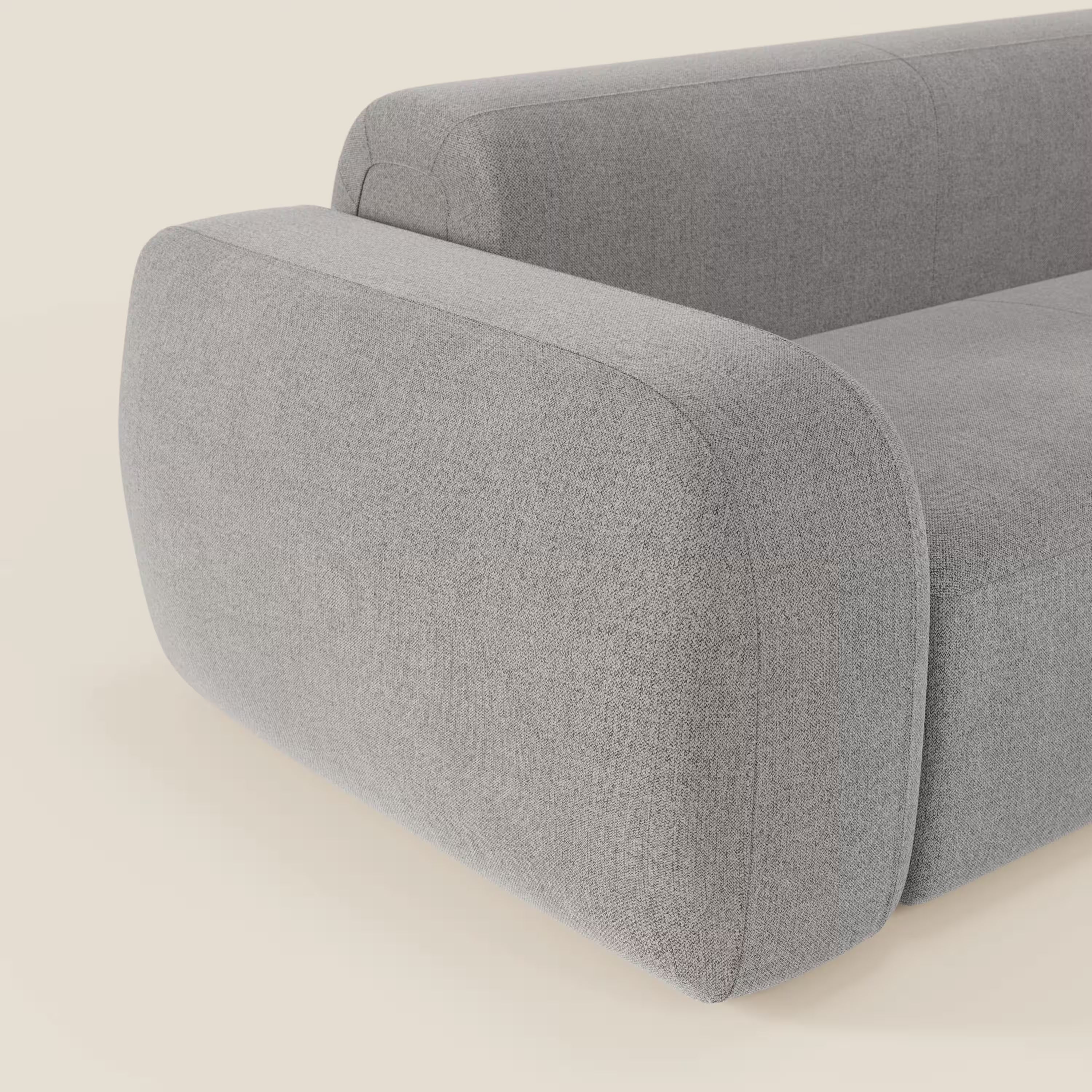 Primo piano del divano componibile BonBon Divano di Divani.Store in tessuto grigio T23 antimacchia, caratterizzato da bordi arrotondati, braccioli spessi e curve morbide per un look contemporaneo e una sensazione di comfort su uno sfondo chiaro.