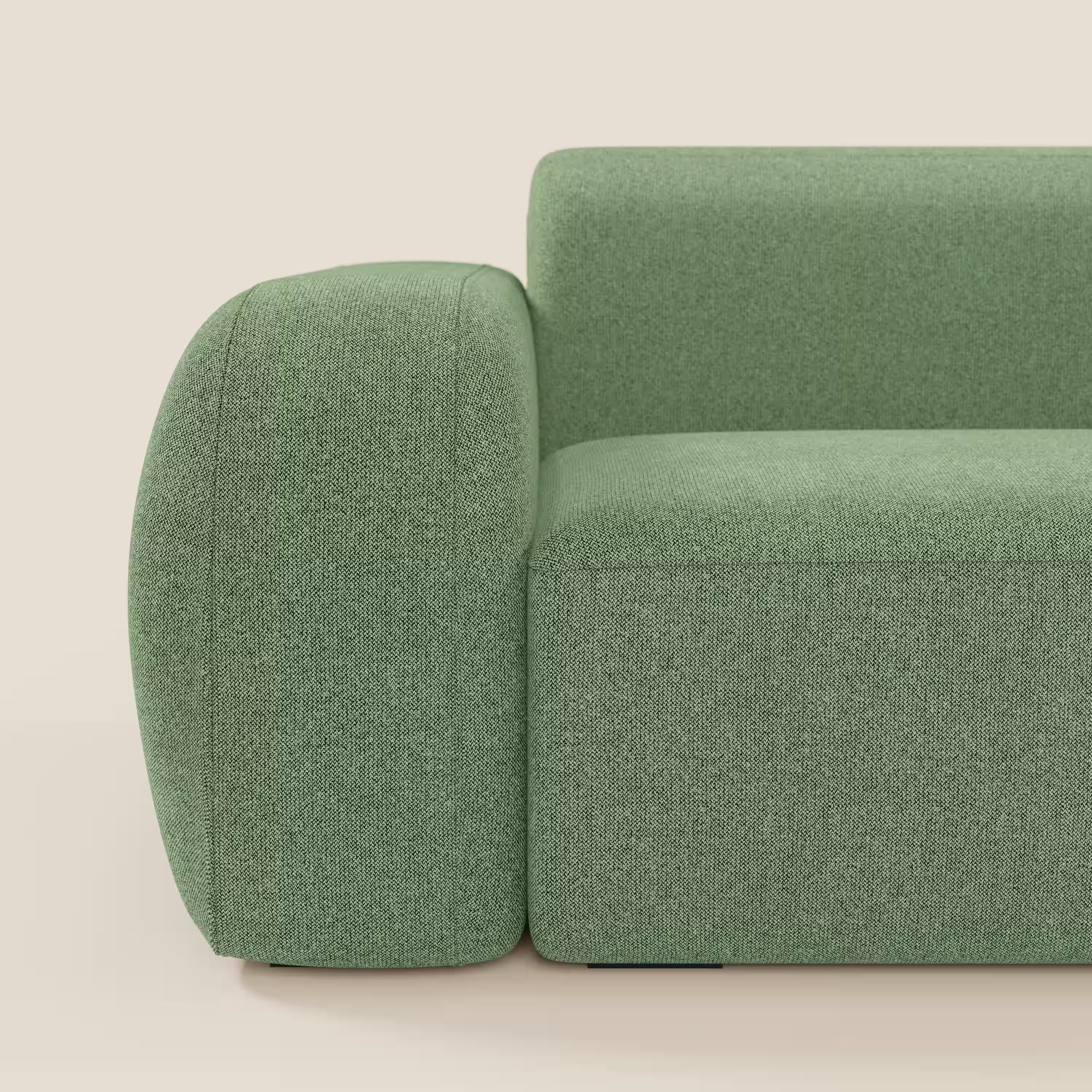 Primo piano di BonBon Divano componibile di Divani.Store in tessuto smacchiabile T23 menta, dal design squadrato e minimalista con bordi arrotondati. La foto mostra il bracciolo sinistro, la seduta e lo schienale su uno sfondo beige chiaro.