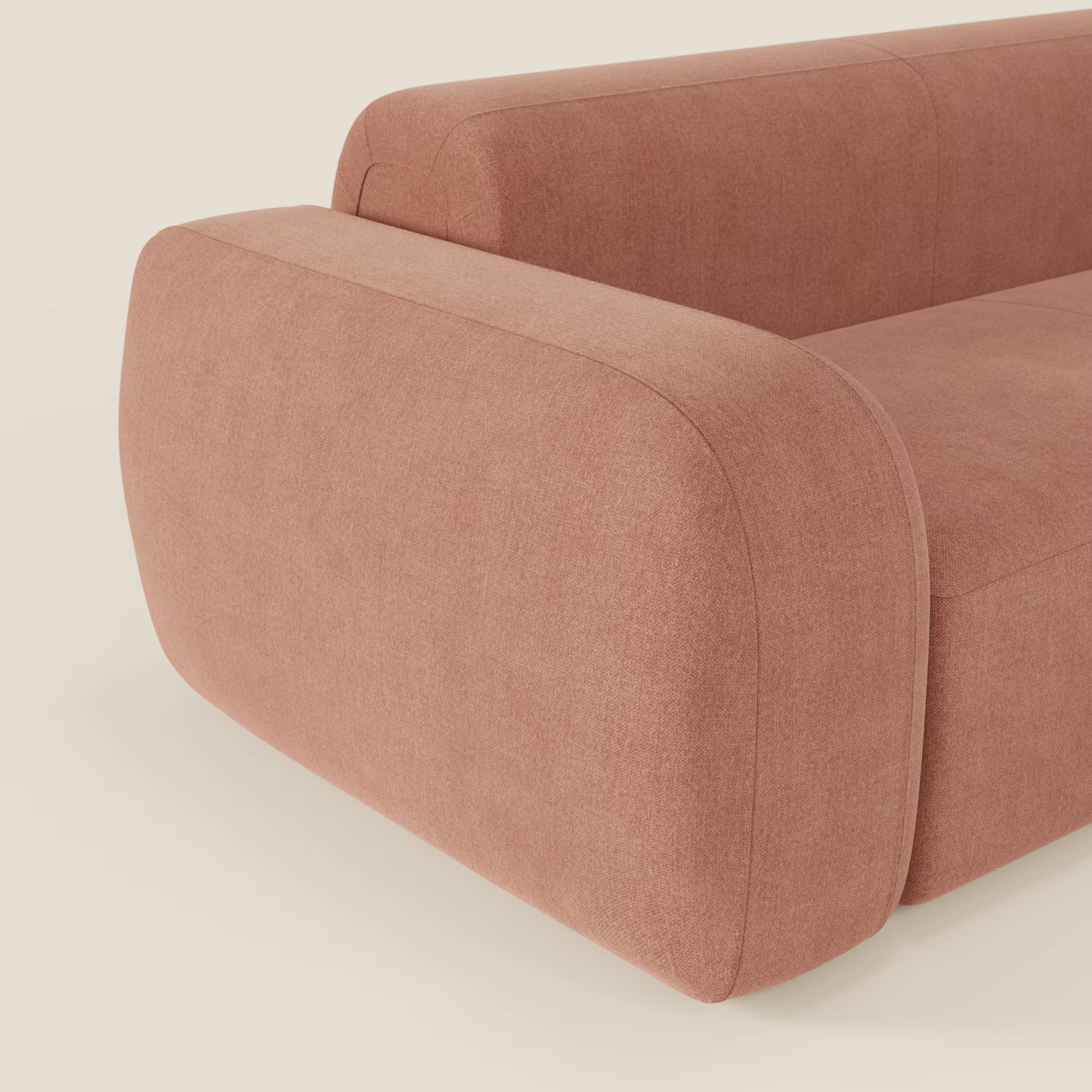 Il Divano componibile BonBon di Divani.Store è caratterizzato da braccioli spessi e arrotondati e da uno schienale in tessuto antimacchia T23 pesca dalle linee morbide e minimaliste; in figura su uno sfondo a tinta unita con un bracciolo e una seduta a vista.