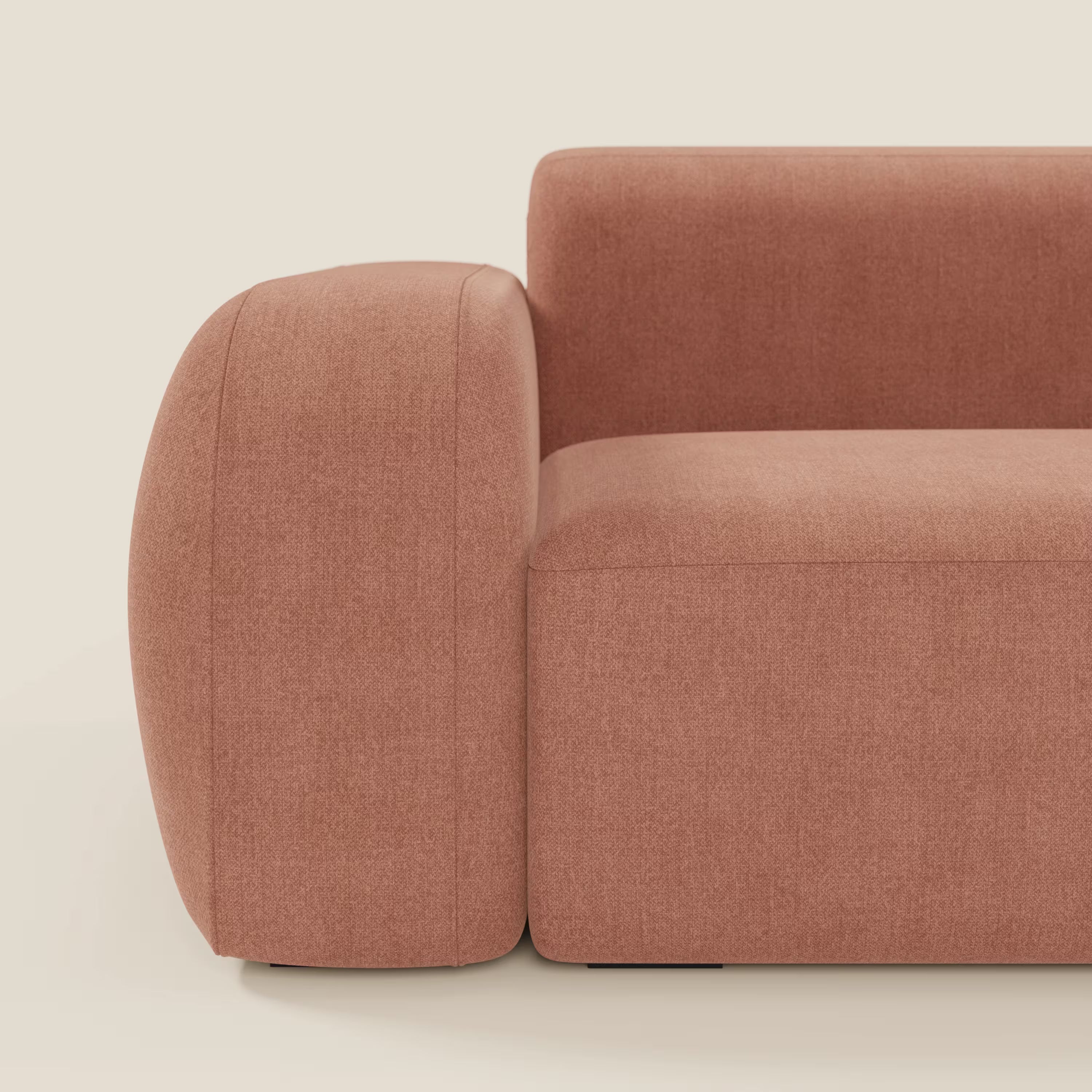 Vista laterale di BonBon Divano componibile di Divani.Store, in tessuto smacchiabile T23 pesca. I braccioli arrotondati e le linee pulite conferiscono un'eleganza minimalista su uno sfondo beige chiaro.