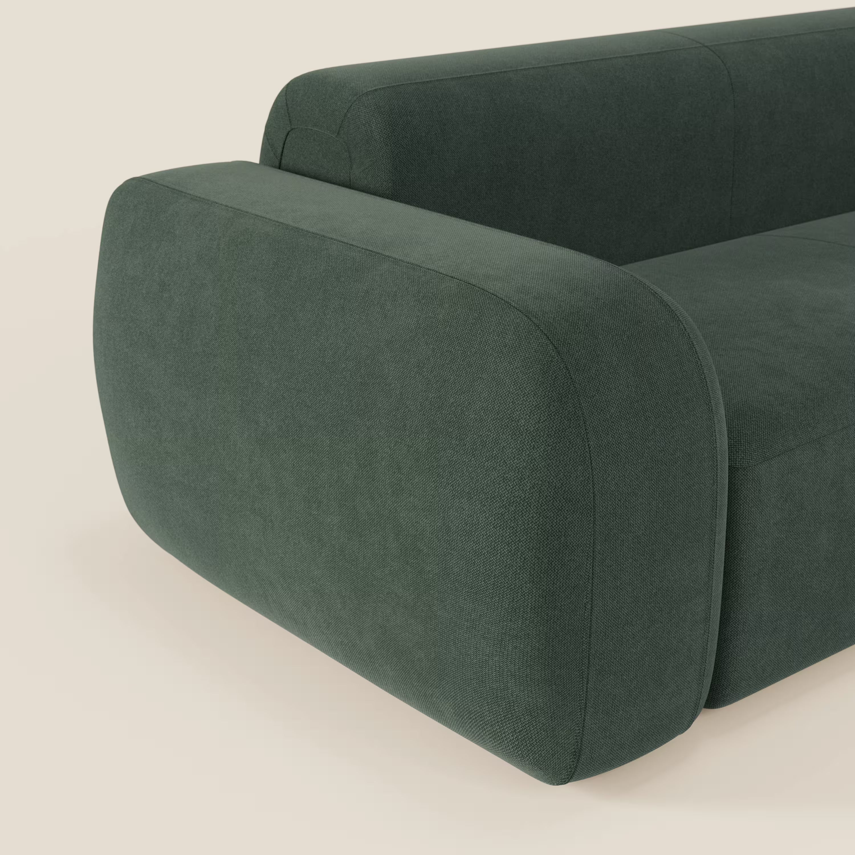 Un primo piano del divano componibile BonBon Divano di Divani.Store in tessuto verde smacchiabile T23 mette in evidenza l'ampio bracciolo sinistro in tessuto felpato e il design minimalista, che offre comfort e stile su uno sfondo chiaro.