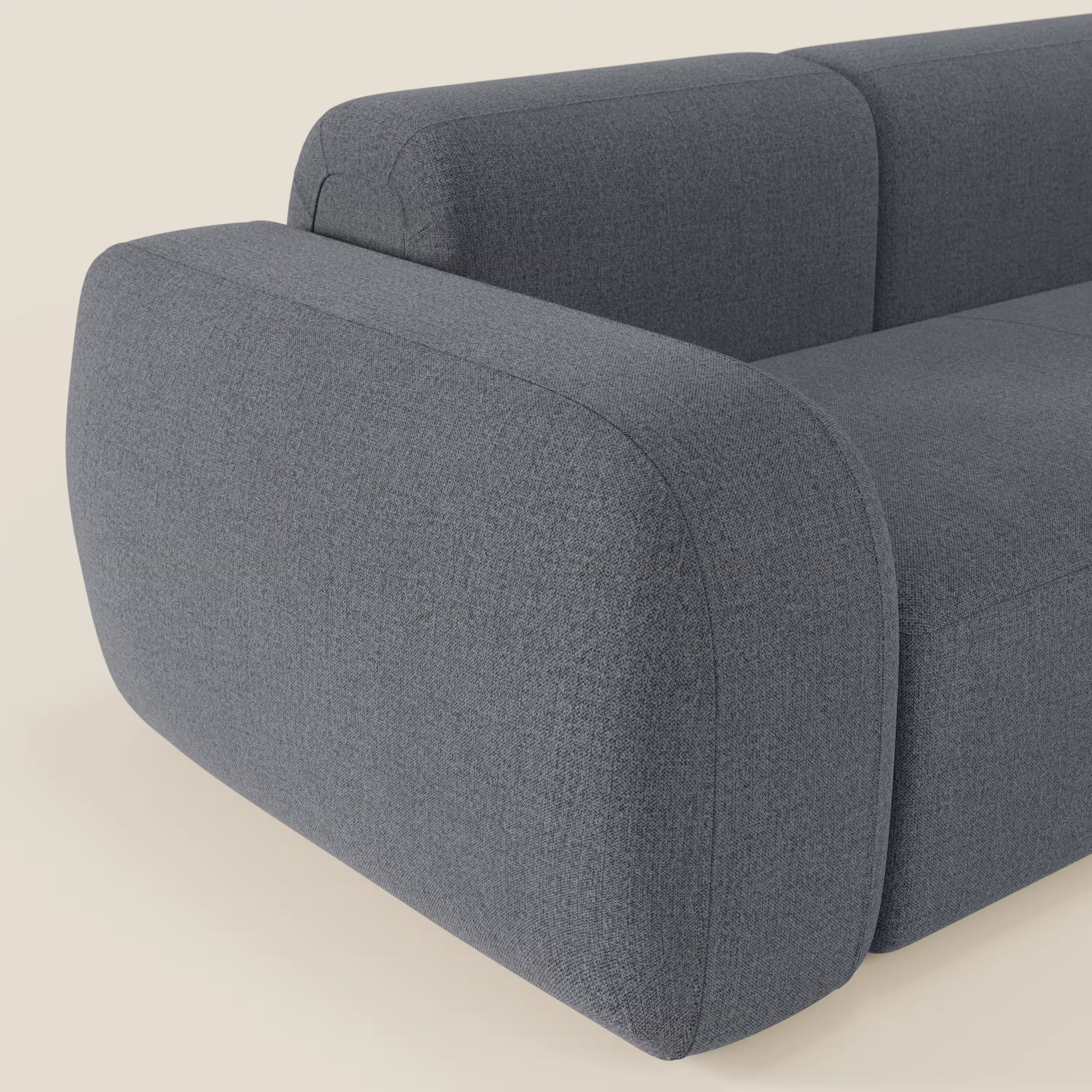 Un primo piano del BonBon Divano componibile - Composizione Spaccamattone di Divani.Store è caratterizzato da braccioli e schienale arrotondati e sovradimensionati in tessuto smacchiabile T23 blu grafite, su sfondo beige chiaro.