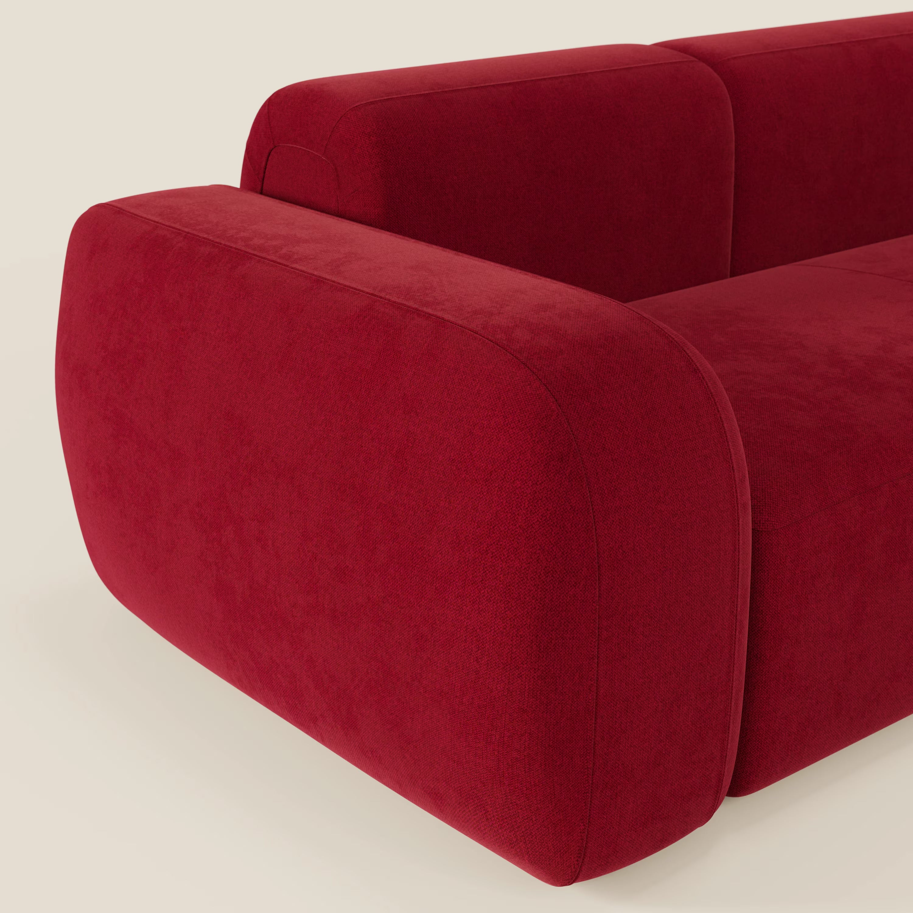 Un primo piano del divano componibile BonBon Divano - Composizione Spaccamattone di Divani.Store in tessuto smacchiabile T23 bordeaux, con bordi arrotondati e braccioli morbidi su uno sfondo chiaro.