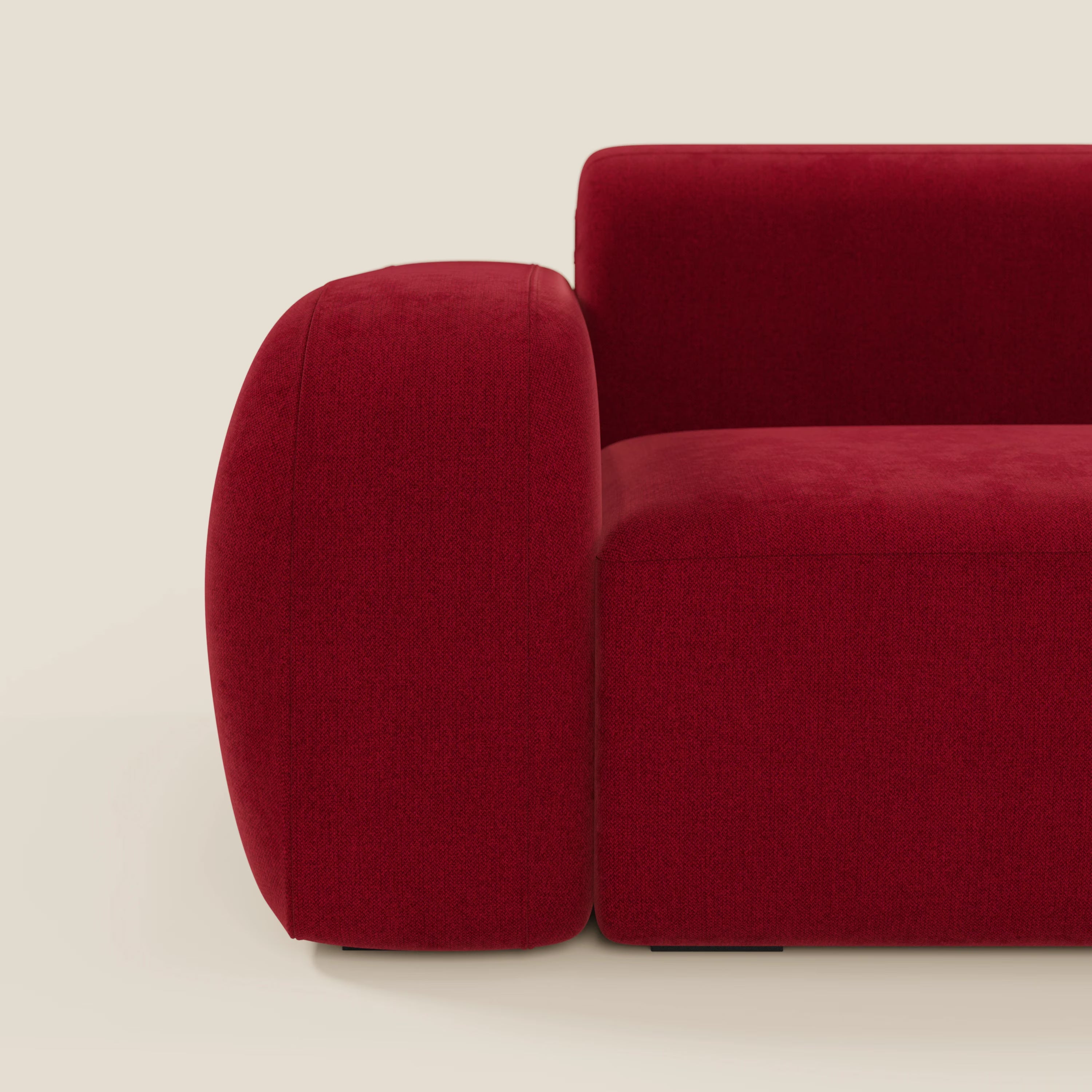 Vista laterale ravvicinata del BonBon Divano componibile - Composizione Spaccamattone in tessuto smacchiabile T23 bordeaux di Divani.Store, caratterizzato da bracciolo e schienale arrotondati e morbidi su un pavimento chiaro con sfondo bianco sporco.