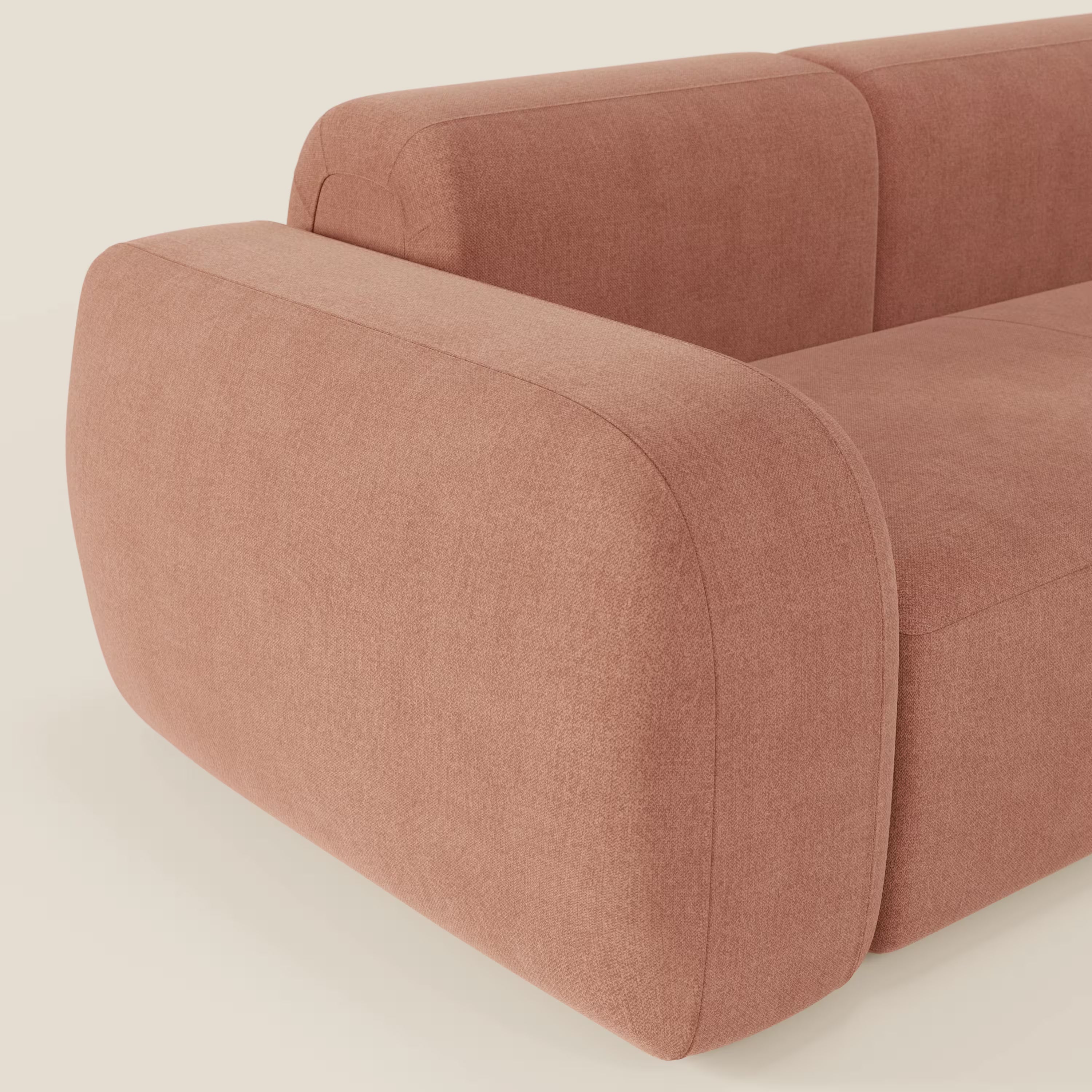 Primo piano del divano componibile BonBon Divano - Composizione Spaccamattone di Divani.Store, in tessuto smacchiabile T23 pesca, con braccioli spessi e arrotondati, seduta morbida e bordi curvi su sfondo neutro.